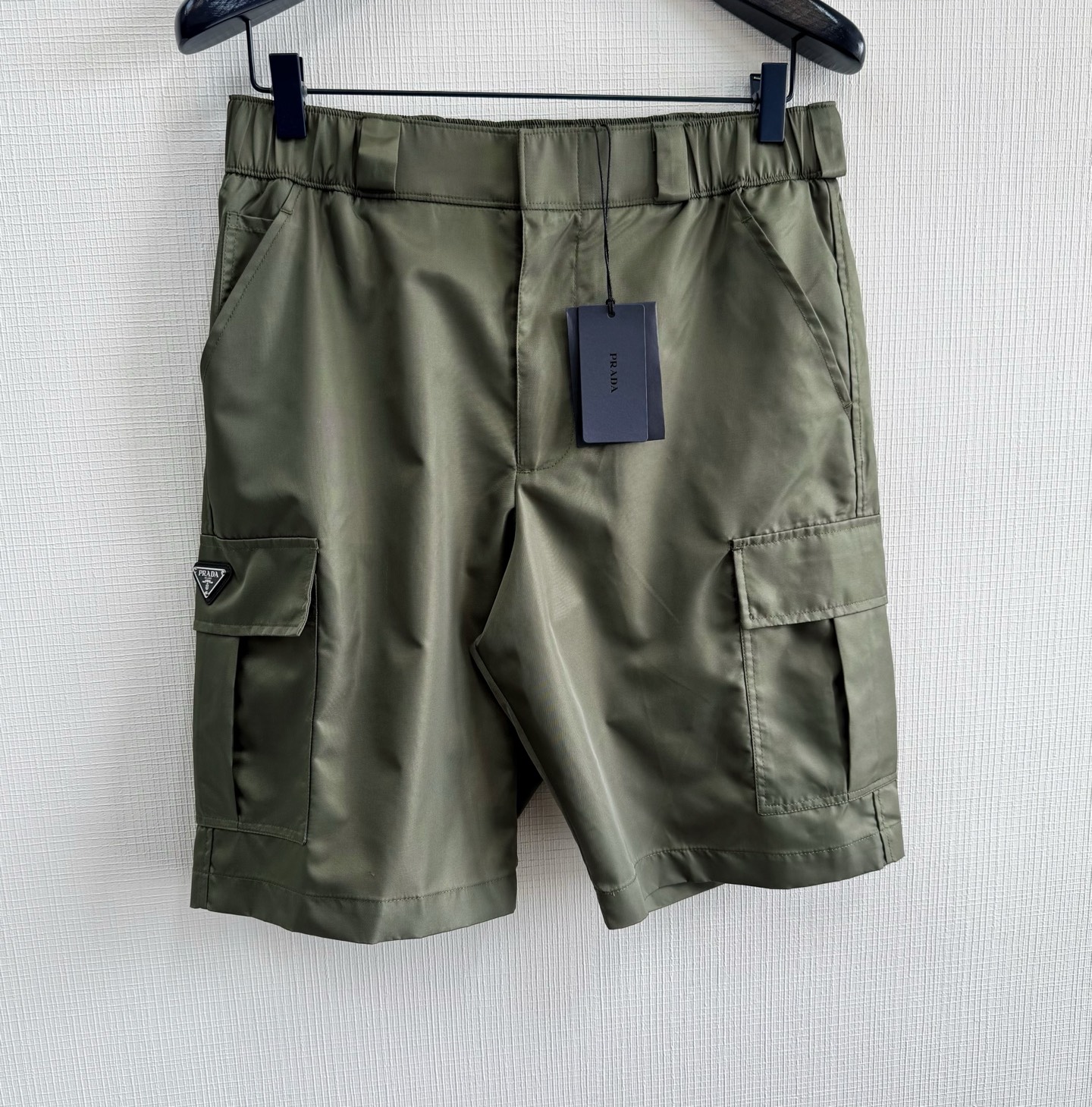 NO:823510,PRA25ss nylon work shorts are made of the iconic high-density woven structure nylon fabric. After surface nano-coating treatment, it has a certain waterproof function without losing breathability. The double-cable cable car hems at the feet are combined with three-needle five-thread lathes. The stitching tension is accurate to 25N, ensuring beautiful routing and enhancing firmness.  The bag knotting process is used to strengthen the bag opening, with a single point load-bearing of 2KG. The utility pocket flap is opened and closed with Velcro, and the triangular logo is decorated on the bag flap to enhance brand recognition. Size: s/m/l/xl, Prada - clothing, prada, prada, shorts,19860909PRA25ss 尼龙工装短裤 标志性高密度的编织结构尼龙面料制成,经过表面纳米涂层处理之后使其具备一定的防水功能,又不失透气性 脚边双线缆车锁边配合三针五线冚车,缝线张力精确至25N,确保走线美观的同时又强化牢固度. 运用口袋套结工艺强化袋口牢固度,单点承重达2KG,工装口袋翻盖魔术贴开合,将三角徽标饰以袋盖之上强化品牌辨识度Size:s/m/l/xl,普拉达-服装,prada,prada,shorts,,Women's clothing