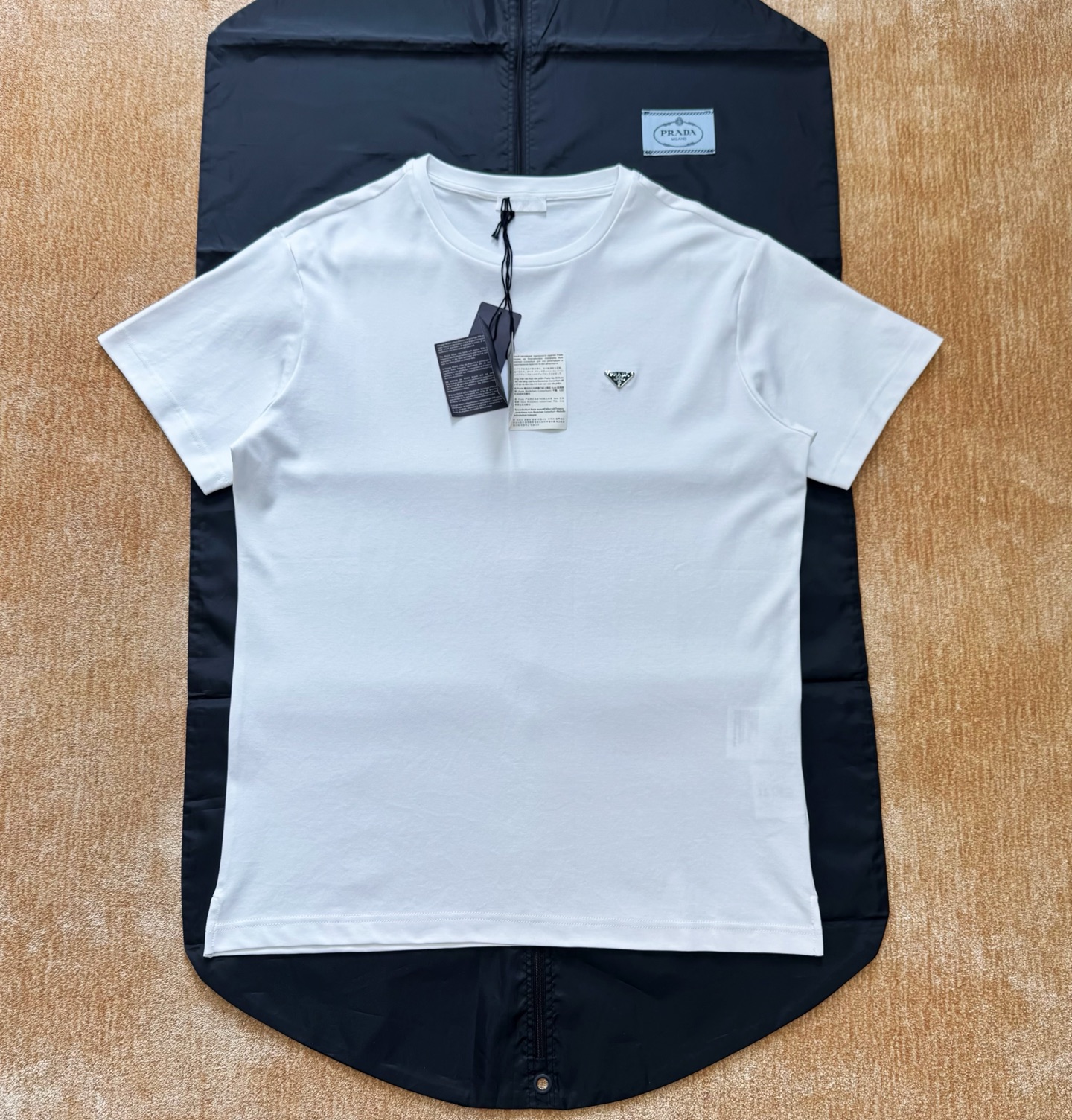 NO:823465,Prad 26ss triangle steel logo T-shirt with chip 180g combed cotton single-sided cloth  The gray fabric is singed and passed through a mercerizing machine to increase its luster. After dyeing in a vat, it is washed and set in liquid ammonia for twelve hours to produce the finished fabric. The fabric has strong anti-wrinkle properties and a glossy surface. The pattern design adopts a triangular fork with a center opening in the front, a fold-back collar pocket on the back panel, and the back collar pocket is swept and positioned with powder, and is sewn with a flat car and hidden stitches.  The finished product has smooth routing, and the front triangular logo is made of pure steel. An integrated mold is opened, and the film is injected and the embryo is produced at one time. Later, the paint is applied and smoothed and the paint is baked to produce the finished product. Size: s/m/l/xl, Prada-clothing, prada, prada, tees, t-shirt,19860909Prad 26ss三角钢标T恤 带芯片 180g 精梳棉单面布 胚布烧毛后过丝光机增加光泽,缸内染色后洗水定型液氨内浸泡十二小时出成品布,布料有极强的抗皱性能且表面带光泽,版型设计采用前中开三角叉,后幅带折汗后领兜,后领兜扫粉定位,平车暗线车缝,成品走线圆顺,前幅三角标采用纯钢材质,开一体化模具,一次注膜出胚,后期点漆抹平烤漆工艺出成品size:s/m/l/xl,普拉达-服装,prada,prada,tees，t-shirt,,Women's clothing