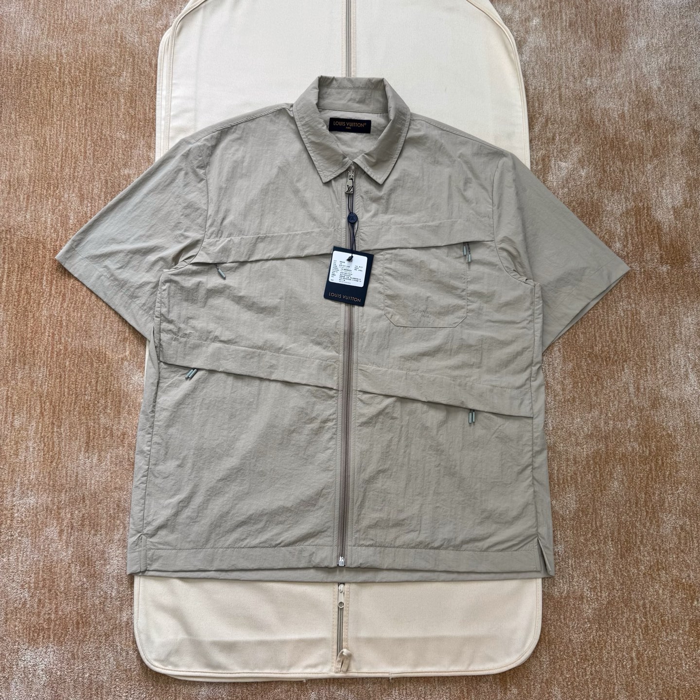 NO:775865,1v 26ss khaki lapel zipper short-sleeved shirt. Technical nylon woven fabric, after special coating or finishing, it can also be water-repellent, windproof and other functionalities. Classic lapel + half-zip design, the collar can be stood up to prevent wind. The main body of the front panel adopts precision stitch embroidery technology. The embroidery is very fine and dense, the letters are clear and the lines and three-dimensional sense are strong. The linen material embroidery thread is combined with encrypted processing, and the embroidery body has a subtle matte visual texture.  There are double zipper drawstring pockets under the waist, which can adjust the elasticity of the hem and increase the storage space. Size: s/m/l/xl, Louis Vuitton-clothing, louis vuitton, shirts, T-shirt,198609091v 26ss 卡其翻领拉链短袖衬衫 科技锦纶梭织面料,特殊涂层或后整理后,还可具备防泼水、防风等功能性,经典翻领+半开拉链设计,领口可立起防风,前幅主体采用精密挨针绣工艺,刺绣非常精细针法绵密,字母清晰且 线条感和立体感强.亚麻材质绣线结合加密处理,绣体具有微妙的哑光视觉质感, 腰部下方配有双拉链抽绳口袋,可调节衣摆松紧,同时增加储物空间Size:s/m/l/xl,路易威登-服装,louis vuitton,shirts,T-shirt,,Women's clothing