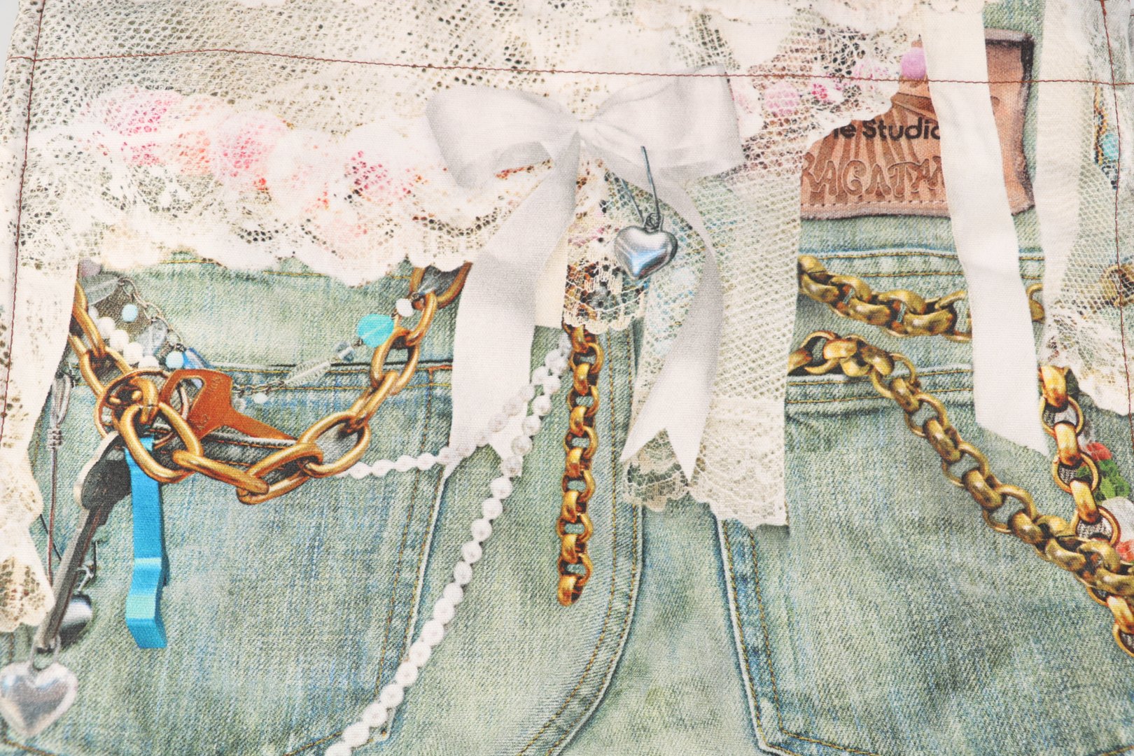 图片[8]-#Acne Studios 25Fw 蕾丝珍珠印花牛仔托特包 采用高密双股纱线织造，克重达420g/㎡，表面呈现粗粝斜纹肌理，同时通过预缩酵素洗处理确保尺寸稳定性，赋予包体挺括骨架感与抗变形性能，选用进口数码直喷机，实现1200dpi高清印花，通过6色纳米墨水层叠渗透技术，将“蕾丝裤”图案以微米级精度附着于帆布纱线间隙，形成立体浮雕触感。匹布印后经UV固化与硅油柔化处理，确保图案耐水洗、抗摩擦，使用兄弟BAS双针平缝机，配置16号钛涂层牛仔针与Tex 70高弹涤纶线，在包体侧缝及底部间距同步车缝双线，形成平行受力通道，分散承重压力。三次元回针加固，在拎手锚点、包角应力区采用电脑程式化回针，配合背面热熔胶衬垫，形成机械-化学双重复合固定，此设计通过材料科学与精密缝制技术的交叉应用，实现柔美意象与重型帆布机能结构的对立统一，体现ACNE对当代工艺美术化的极致追求 尺码：47×17×35-选品中心