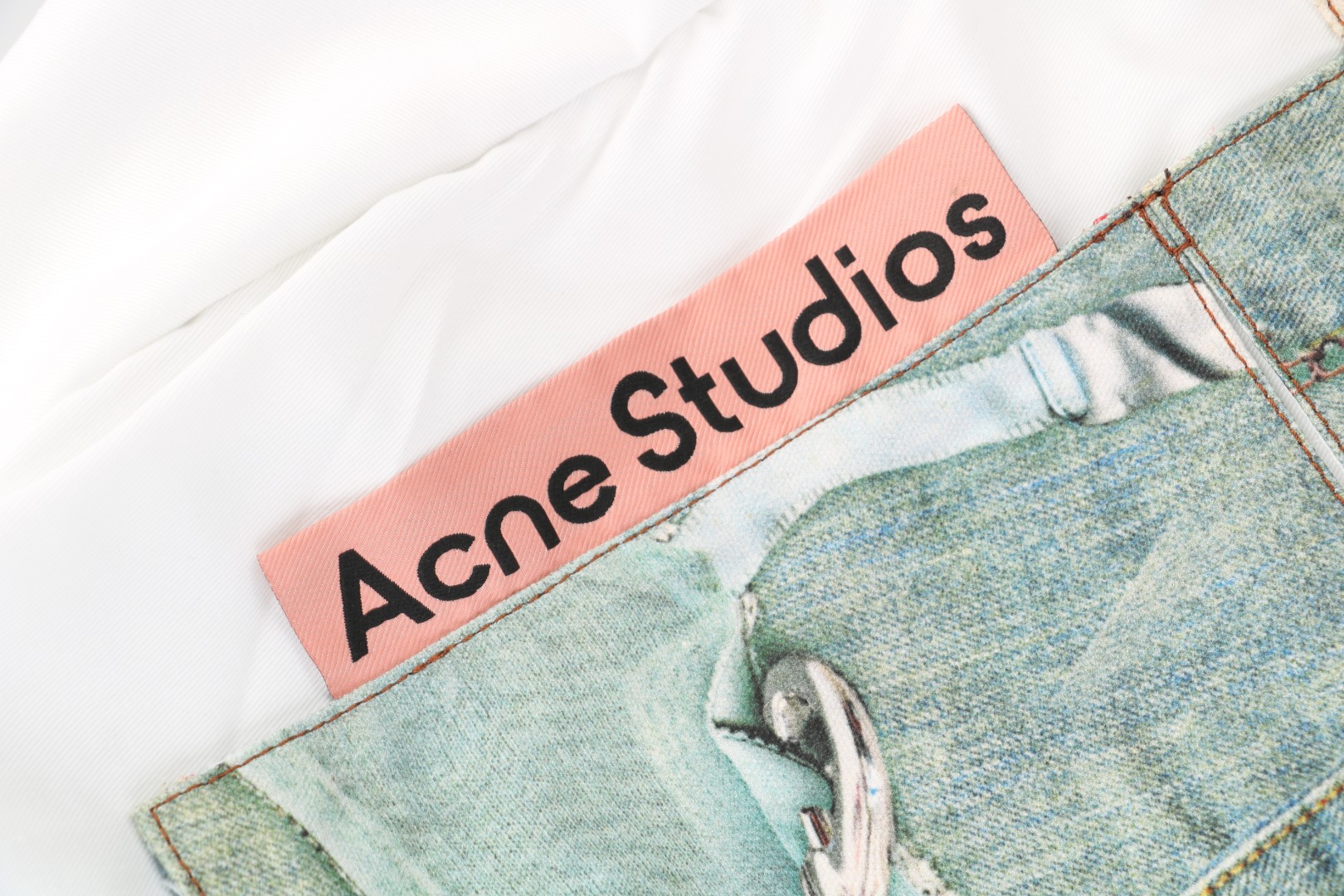 图片[4]-#Acne Studios 25Fw 蕾丝珍珠印花牛仔托特包 采用高密双股纱线织造，克重达420g/㎡，表面呈现粗粝斜纹肌理，同时通过预缩酵素洗处理确保尺寸稳定性，赋予包体挺括骨架感与抗变形性能，选用进口数码直喷机，实现1200dpi高清印花，通过6色纳米墨水层叠渗透技术，将“蕾丝裤”图案以微米级精度附着于帆布纱线间隙，形成立体浮雕触感。匹布印后经UV固化与硅油柔化处理，确保图案耐水洗、抗摩擦，使用兄弟BAS双针平缝机，配置16号钛涂层牛仔针与Tex 70高弹涤纶线，在包体侧缝及底部间距同步车缝双线，形成平行受力通道，分散承重压力。三次元回针加固，在拎手锚点、包角应力区采用电脑程式化回针，配合背面热熔胶衬垫，形成机械-化学双重复合固定，此设计通过材料科学与精密缝制技术的交叉应用，实现柔美意象与重型帆布机能结构的对立统一，体现ACNE对当代工艺美术化的极致追求 尺码：47×17×35-选品中心