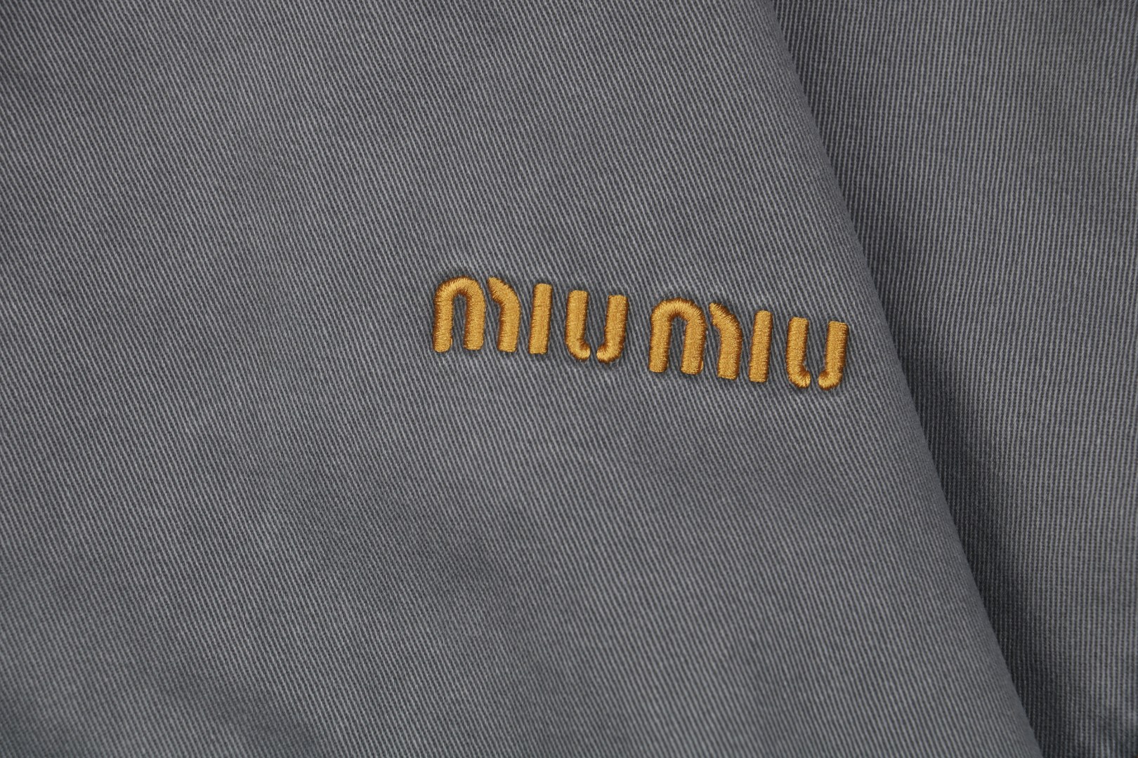 图片[5]-#Miu Miu 25Fw Miu小标灯芯绒领做旧棉服外套 定制进口12oz斜纹编织丹宁面料，纱线经环锭纺处理，保留粗粝肌理。采用臭氧洗+浮石擦洗，在袖口、肩部等受力区域模拟自然穿着痕迹，选用高克重纯棉灯芯绒，绒条宽度为复古8W，确保纹理立体且触感细腻。通过酶洗+砂洗处理，使绒面呈现自然褪色效果，边缘处手工打磨做旧，强化Vintage风格，使用进口田岛多头刺绣机，以0.3mm极细针脚还原logo或图案的微渐变效果。 Amann Serafil涤棉混纺线，色牢度达4级以上，确保水洗后不晕色。底层覆盖可溶解衬布，刺绣完成后高温冲洗，形成立体浮雕感且无硬衬残留，内里填充1000D洗水棉（经预缩处理），采用箱式绗缝分仓填充，每格充棉量精确至±3%误差，避免局部凹陷。 通过克重调节在轻盈度与保暖性间取得平衡，此款夹克通过上述工艺链实现“设计感”与“耐穿性”的统一，堪称当代解构主义工装的高级诠释 尺码：38 40 42-选品中心