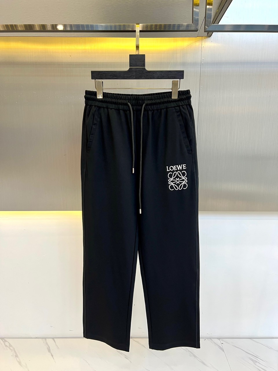 NO:439889,Luo Yiwei and spring and summer new fashionable letter embroidered casual pants for men's wide drawstring trousers. The cotton fiber blended fabric is light and luxurious, with a delicate touch and excellent breathability, as if it is covered with a layer of soft clouds on the skin. This high-end blended fabric not only shows an extraordinary texture, but also gives the wearer a unique elegant temperament. The classic badge embroidery design on the front shows the unique charm of the brand, and the retro and trendy atmosphere intertwines it, showing a unique fashion taste. The high-elastic drawstring elastic waist design is not only easy to put on and take off, but also freely adjusts according to the personal waistline. Whether it is tight or loose style, it can be easily controlled!  M-3XL (please report height and weight by placing an order), loewe, alexander wang19860909罗意威、春夏新款时尚字母刺绣休闲裤男士宽筒抽绳长裤.甄选客供棉质纤维混纺面料,质地轻盈而奢华,触感细腻如丝,透气性极佳,仿佛为肌肤披上了一层轻柔的云朵.这种高级混纺面料不仅展现出非凡的质感,更赋予了穿着者一种独特的优雅气质.前幅的经典徽章刺绣设计,细节之处彰显品牌的独特魅力,复古与潮流的气息交织其中,展现出与众不同的时尚品味.高弹力的抽绳松紧裤腰设计,不仅方便穿脱,更可根据个人腰围自由调节,无论是紧身搭配还是宽松风格,都能轻松驾驭！M-3XL（下单请报身高体重）,,loewe,alexander wang,Men's clothing