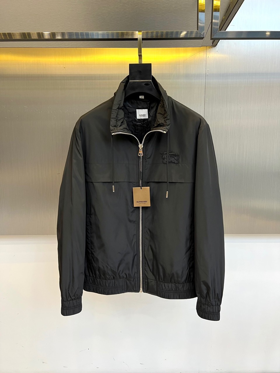 NO:514436,Burberry, 25s autumn and winter new stand-up collar jacket jacket classic reshaping, details are real. Soft beige fabric is like autumn wheat waves, matched with three-dimensional stand-up collar and drawstring design, outlining neat silhouettes in a metal texture background. The left chest BURBERRY embroidered logo is presented in matte silk thread, just like the dark-patterned collar pin on a gentleman's suit, low-key but not neglected. The secret is hidden inside. Open the jacket, the Laurel Leaf lining label is like a secret medal, and paired with a double-language wash mark to show the exquisite consideration of globalization. The military-grade car line of the elastic cuffs and hem injects the rigorous craftsmanship of Savile Row into modern functional design. The three-second switching styling philosophy Zipper tied up stand-up collars, instantly transformed into an urban explorer. The drawstring relaxes with a sweater, interpreting the lazy London accent  The fabric under the metal halo will breathe - windproof material contains breathable hole technology. Wearing equations are worn with dark gray turtleneck + black jogging pants, and the collar is colliding with color blocks to highlight the architectural feel of the stand-up collar 48-56 (model 173, 143 catties upper body 50 yards), burberry, burberry, jackets & coats, jackets & coats, business suit, alexander wang19860909Bur巴宝莉、25s秋冬新品立领夹克外套 经典重塑,细节见真章 柔润米黄色面料如秋日麦浪,搭配立体立领与抽绳设计,在金属质感背景中勾勒出利落剪影.左胸BURBERRY刺绣徽标以哑光丝线呈现,恰似绅士西装上的暗纹领针,低调却不容忽视. 内里暗藏玄机 翻开夹克,Laurel Leaf衬里标签如隐秘勋章,搭配双语言洗标彰显全球化的精致考量.松紧袖口与下摆的军工级车线,将Savile Row的严谨工艺注入现代机能设计. 三秒切换的造型哲学 拉链全系立领,即刻变身都市探险者 抽绳放松搭配针织衫,演绎慵懒伦敦腔调 金属光晕下的面料会呼吸——防风材质内藏透气孔道科技 穿搭方程式内搭深灰高领+黑色慢跑裤,用色块碰撞凸显立领建筑感 48-56（模特173,143斤上身50码）,,burberry,burberry,jackets & coats,jackets & coats,business suit,alexander wang,Men's clothing