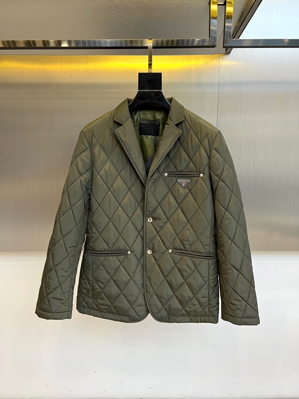 NO:514453,Prada and 25s new products are available for dark green diamond-shaped cotton clothing | British gentleman's winter armor Deep dark green diamond-shaped quilting is like the Scottish tundra, three brass buttons are arranged diagonally along the suit collar, recreating the golden ratio of Savile Row. The dark-texture logo pocket on the left and the symmetrical insert bag form a functional aesthetic, and flows the aristocratic atmosphere under the cold light of the silver metal wall. The temperature philosophy of technology fabrics 82.1 Polyamide + 17.9 Elastic fiber creates a second skin-like dynamic fit Polyester fiber lining is like a velvet barrier, locking the body temperature without being bloated The six languages ​​on the wash mark are Prada's global quality control silent declaration 1. All buttons + neckline stand up = Financial City Elite mode 2. Unlock the first button to reveal the plaid lining = Weekend gallery mode 3.  When the warm yellow light passes, the diamond will show leather-like three-dimensional light and shadow 48-56 (model 173, 143 catties upper body 50 yards), prada, business suit, gold, alexander wang19860909普拉达、25s新品发售墨绿菱格棉服 | 英伦绅士的冬日铠甲 深邃墨绿色菱格绗缝如苏格兰苔原,三颗黄铜纽扣沿西装领斜向排列,重现Savile Row的黄金比例.左侧暗纹徽标口袋与对称插袋构成功能美学,在银色金属墙面的冷光下流转贵族气息. 科技面料的温度哲学 82.1聚酰胺+17.9弹性纤维打造第二层肌肤般的动态贴合 聚酯纤维内衬如丝绒屏障,锁住体温不显臃肿 洗标上的六国语言,是普拉达全球化品控的无声宣言 1. 纽扣全系+领口立起=金融城精英模式 2. 解开首颗纽扣露出格纹内衬=周末画廊模式 3. 暖黄灯光掠过时,菱格会呈现皮革般的立体光影 48-56（模特173,143斤上身50码）,,prada,business suit,gold,alexander wang,Men's clothing