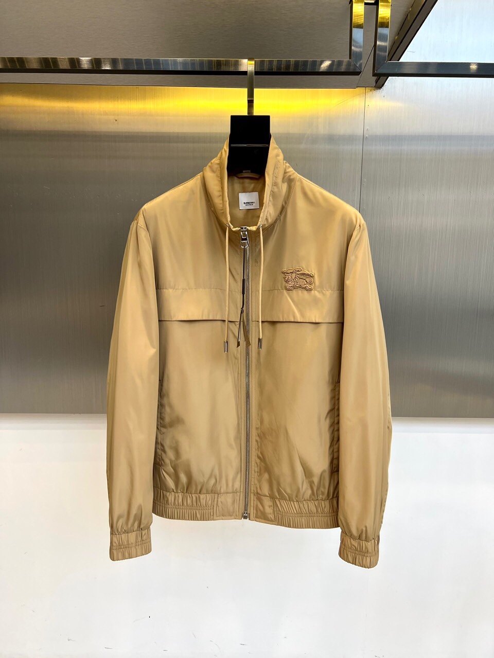 NO:513601,Burberry, 25s autumn and winter new stand-up collar jacket jacket classic reshaping, details are real. Soft beige fabric is like autumn wheat waves, matched with three-dimensional stand-up collar and drawstring design, outlining neat silhouettes in a metal texture background. The left chest BURBERRY embroidered logo is presented in matte silk thread, just like the dark-patterned collar pin on a gentleman's suit, low-key but not neglected. The secret is hidden inside. Open the jacket, the Laurel Leaf lining label is like a secret medal, and paired with a double-language wash mark to show the exquisite consideration of globalization. The military-grade car line of the elastic cuffs and hem injects the rigorous craftsmanship of Savile Row into modern functional design. The three-second switching styling philosophy Zipper tied up stand-up collars, instantly transformed into an urban explorer. The drawstring relaxes with a sweater, interpreting the lazy London accent  The fabric under the metal halo will breathe - windproof material contains breathable hole technology. Wearing equations are worn with dark gray turtleneck + black jogging pants, and the collar is colliding with color blocks to highlight the architectural feel of the stand-up collar 48-56 (model 173, 143 catties upper body 50 yards), burberry, burberry, jackets & coats, jackets & coats, business suit, alexander wang19860909Bur巴宝莉、25s秋冬新品立领夹克外套 经典重塑,细节见真章 柔润米黄色面料如秋日麦浪,搭配立体立领与抽绳设计,在金属质感背景中勾勒出利落剪影.左胸BURBERRY刺绣徽标以哑光丝线呈现,恰似绅士西装上的暗纹领针,低调却不容忽视. 内里暗藏玄机 翻开夹克,Laurel Leaf衬里标签如隐秘勋章,搭配双语言洗标彰显全球化的精致考量.松紧袖口与下摆的军工级车线,将Savile Row的严谨工艺注入现代机能设计. 三秒切换的造型哲学 拉链全系立领,即刻变身都市探险者 抽绳放松搭配针织衫,演绎慵懒伦敦腔调 金属光晕下的面料会呼吸——防风材质内藏透气孔道科技 穿搭方程式内搭深灰高领+黑色慢跑裤,用色块碰撞凸显立领建筑感 48-56（模特173,143斤上身50码）,,burberry,burberry,jackets & coats,jackets & coats,business suit,alexander wang,Men's clothing