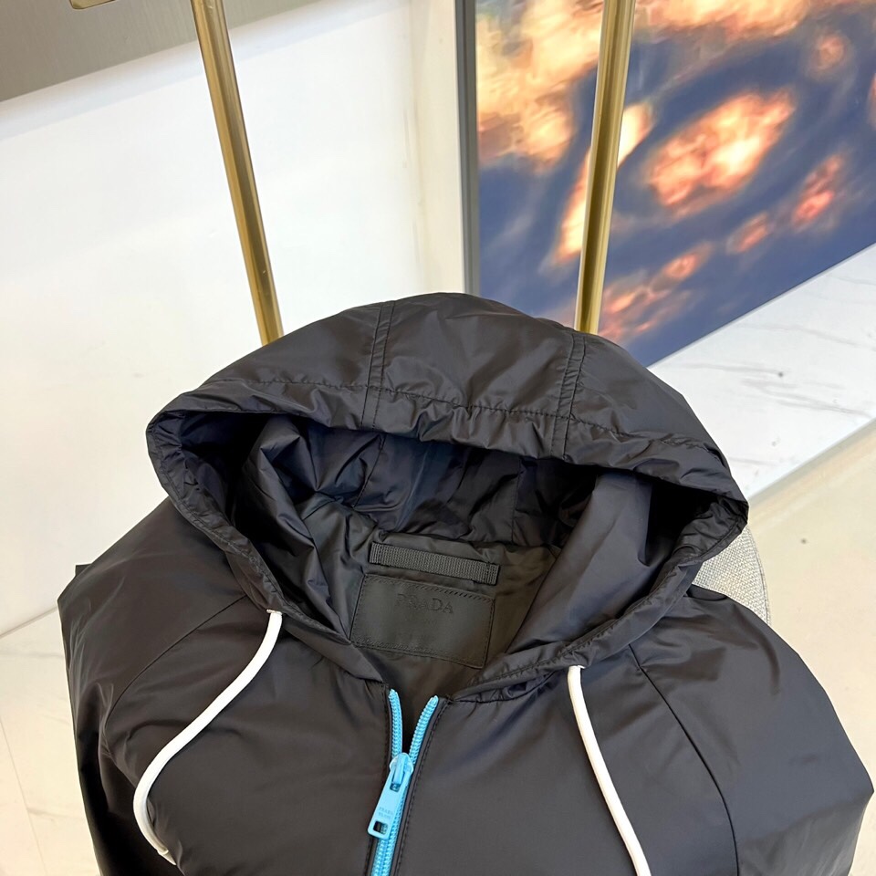 
Prad普拉、25FW黑色机能风连帽夹克外套

哑光尼龙面料打造轻盈防水性能，标志性蓝色拉链与白色抽绳