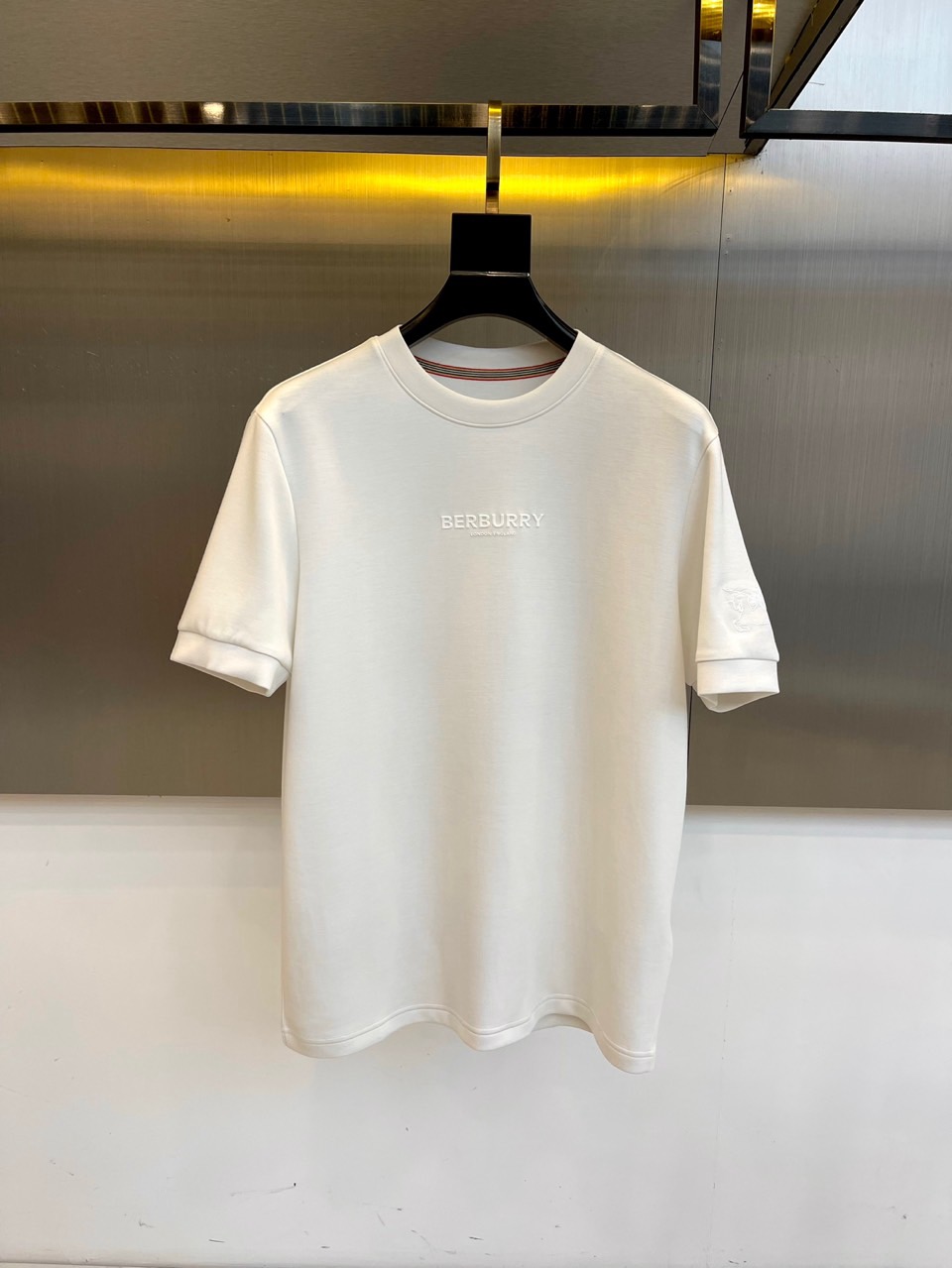 NO:515697,Burberry, 2025 autumn and winter mid-sleeved base shirt, the words 'BURBERRY' are like modern road signs by the Thames River. The inner red, white and blue stripes on the collar are hidden in British blood - this is a pure canvas dedicated to urban gentlemen by a century-old brand. The gold ratio of 53 modal + 22 acrylic + 15 polyester fiber spandex has passed the GB18401 Class B safety certification. The unique blended fabric has soft elasticity and crisp texture, making this base shirt a second layer of skin close to the body. The morning suit is the elite of City, and the three-color stripes are worn alone at night to become a casual gentleman. When the metal wall reflects the luster of the fabric, you will know that the true British style lies in the extraordinary in simplicity. 48-56 (model 173, 143 catties upper body 50 yards), ,burberry, burberry, business  suit, gold,alexander wang19860909Bur巴宝莉、2025秋冬中袖打底衫,'BURBERRY'字样如泰晤士河畔的现代路标,衣领内侧红白蓝三色条纹暗藏英式血统——这是百年品牌献给都市绅士的纯净画布. 53莫代尔+22腈纶+15聚酯纤维氨纶的黄金配比,通过GB18401 B类安全认证.独特混纺面料兼具柔软弹性与挺括质感,让这件打底衫成为贴身的第二层肌肤. 晨间搭配西装是City的精英,夜晚单穿露出三色条纹成为休闲绅士.当金属墙面折射出织物光泽,方知真正的英伦风格在于简约中的不凡.48-56（模特173,143斤上身50码）,,burberry,burberry,business suit,gold,alexander wang,Men's clothing