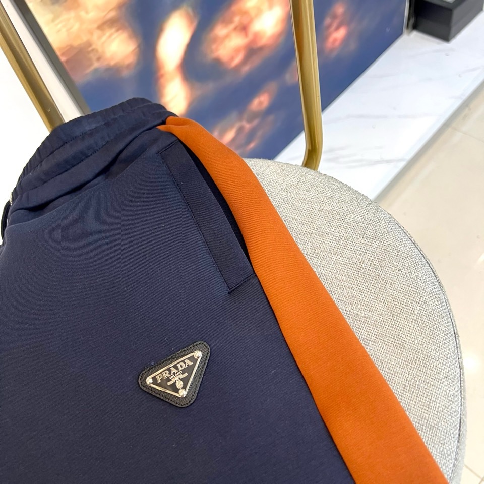 Prad普拉、2025秋冬运动系列。高密弹力面料构筑立体剪裁套装，橙棕条纹如赛道轨迹贯穿袖管与裤线。金属