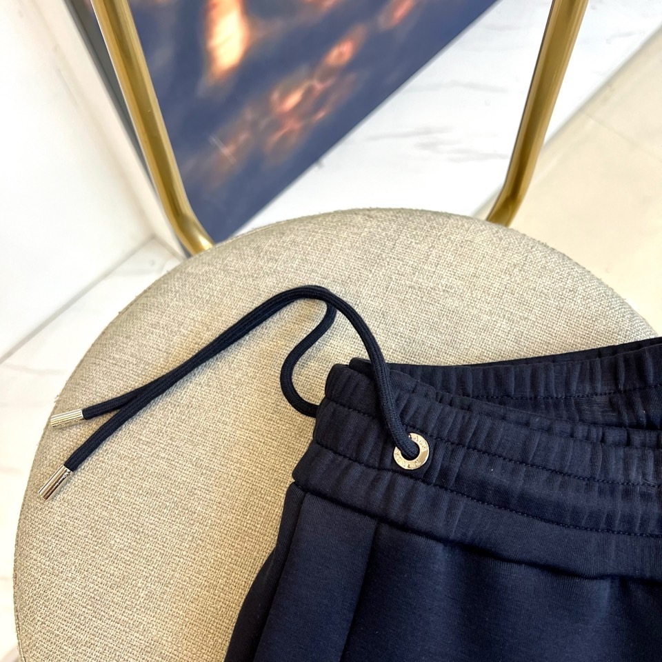 Prad普拉、2025秋冬运动系列。高密弹力面料构筑立体剪裁套装，橙棕条纹如赛道轨迹贯穿袖管与裤线。金属