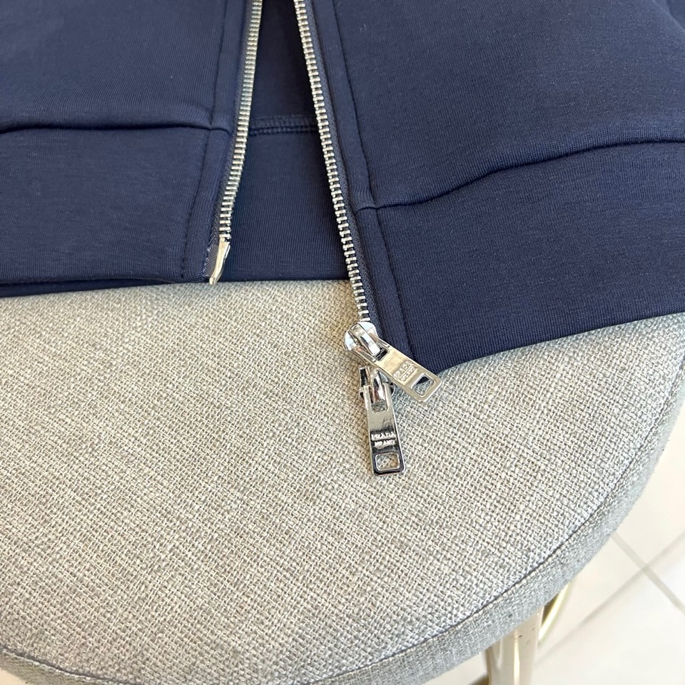 Prad普拉、2025秋冬运动系列。高密弹力面料构筑立体剪裁套装，橙棕条纹如赛道轨迹贯穿袖管与裤线。金属