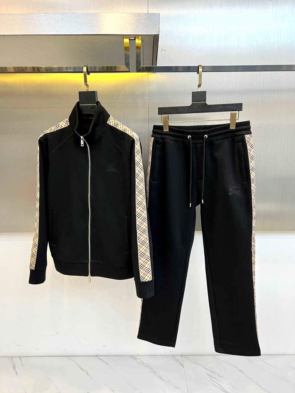 Bur巴宝莉、2025秋冬新款运动套装，以纯黑为基底，将Burberry标志性格纹元素贯穿袖侧与裤缝。高