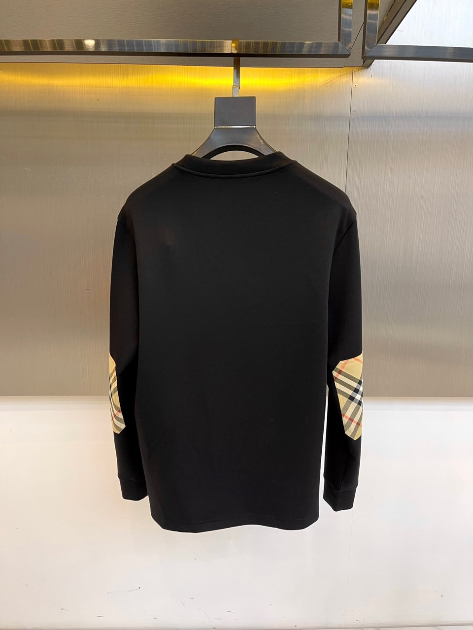 巴宝莉、2025秋冬长袖打底衫。左胸椭圆形金色徽标镌刻品牌基因，领口内侧格纹暗藏经典传承——这是PRAD