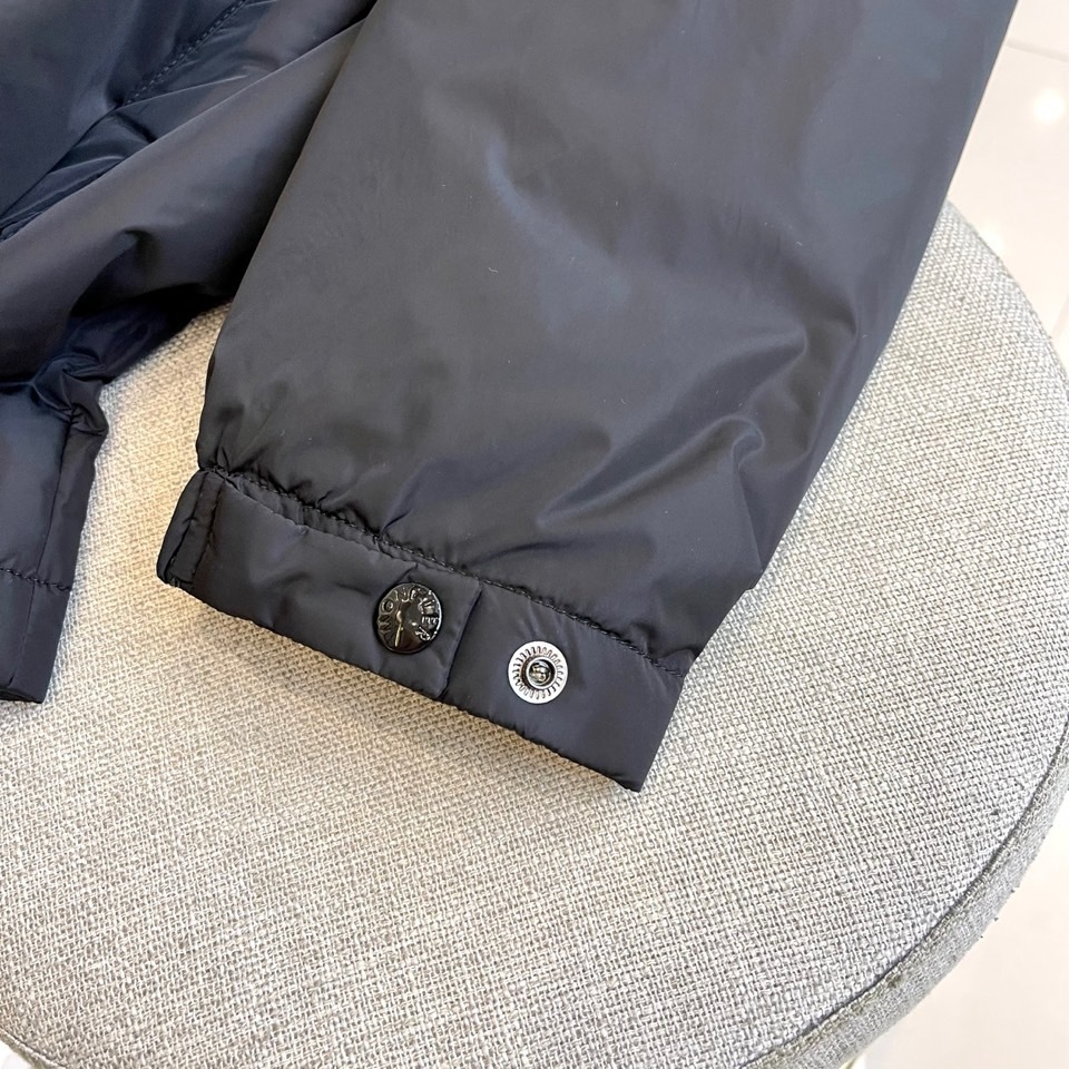 Mon蒙口、2025秋冬连帽棉服夹克外套。MONCLER黑色连帽羽绒服,以立体绗缝工艺勾勒雪域轮廓。肩带