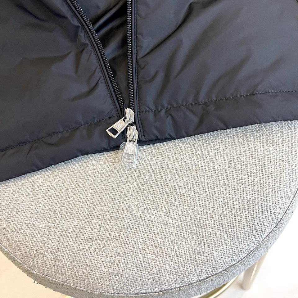 Mon蒙口、2025秋冬连帽棉服夹克外套。MONCLER黑色连帽羽绒服,以立体绗缝工艺勾勒雪域轮廓。肩带