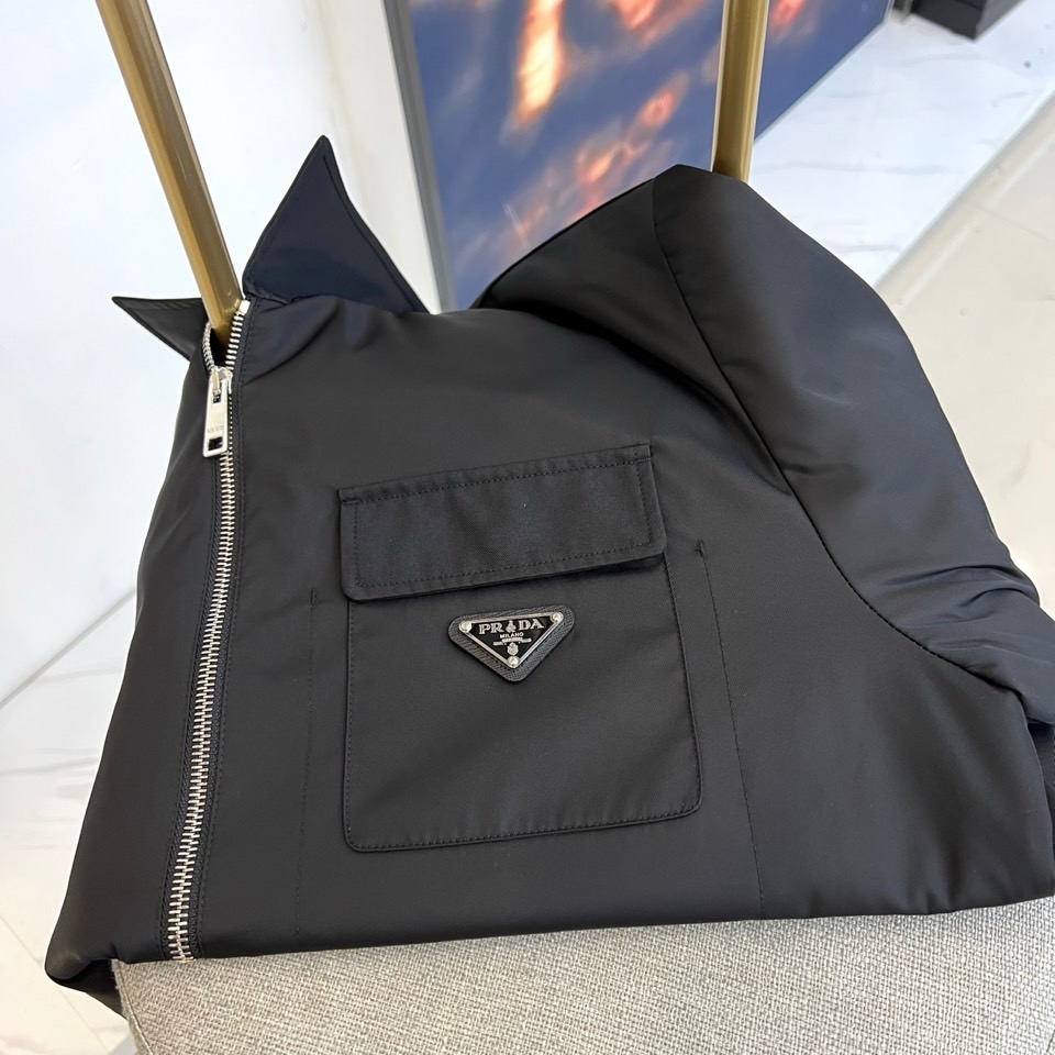Prada 2025秋冬夹克。【高品质】这款Re-Nylon衬衫廓形简约流畅，融入运动细节，饰以涂珐琅三