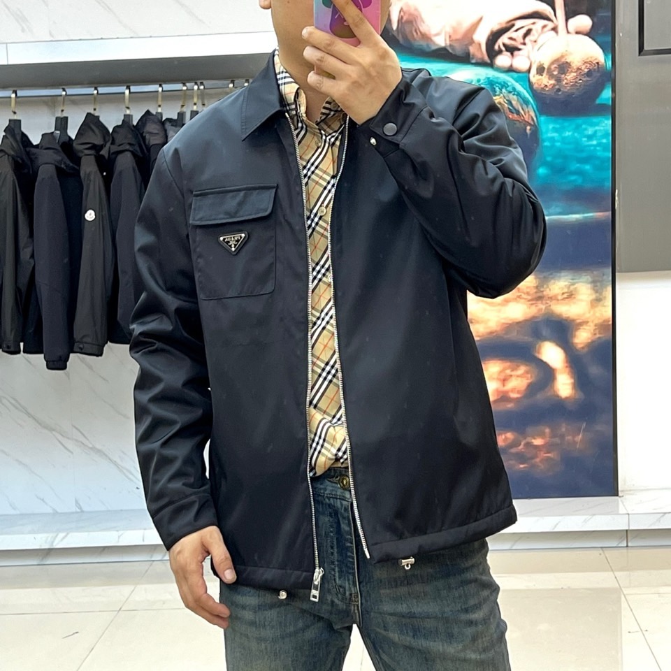 Prada 2025秋冬夹克。【高品质】这款Re-Nylon衬衫廓形简约流畅，融入运动细节，饰以涂珐琅三