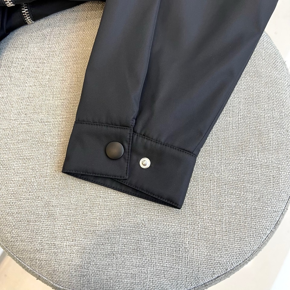 Prada 2025秋冬夹克。【高品质】这款Re-Nylon衬衫廓形简约流畅，融入运动细节，饰以涂珐琅三