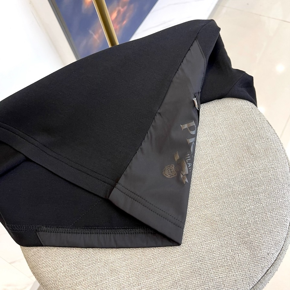 Prad普拉、2025秋冬长袖T恤卫衣。左胸椭圆形金色徽标镌刻品牌基因，领口内侧格纹暗藏经典传承——这是