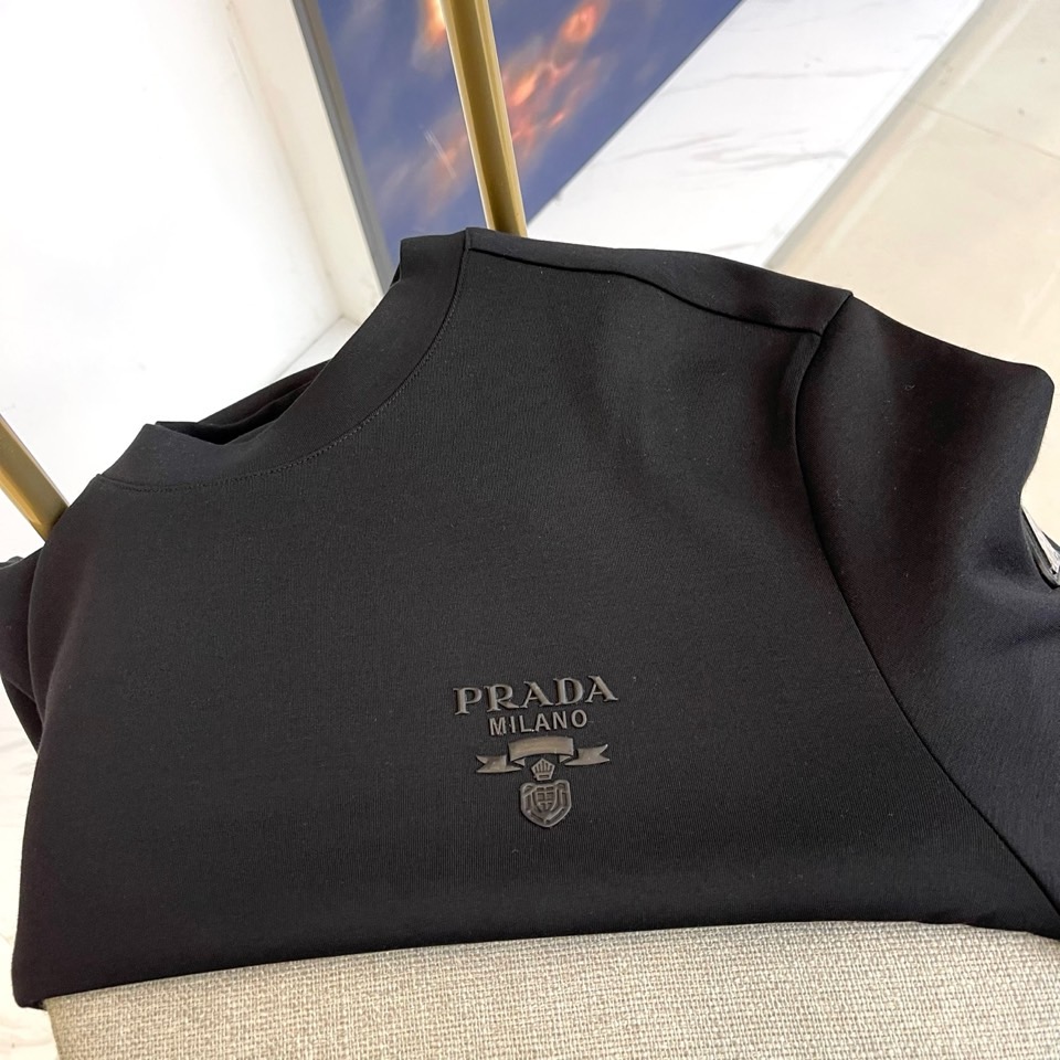 Prad普拉、2025秋冬长袖T恤卫衣。左胸椭圆形金色徽标镌刻品牌基因，领口内侧格纹暗藏经典传承——这是