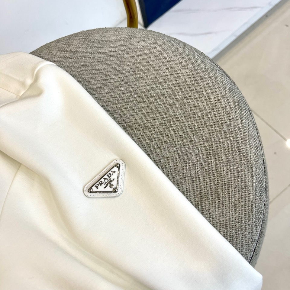 Prad普拉、2025秋冬长袖T恤卫衣。左胸椭圆形金色徽标镌刻品牌基因，领口内侧格纹暗藏经典传承——这是