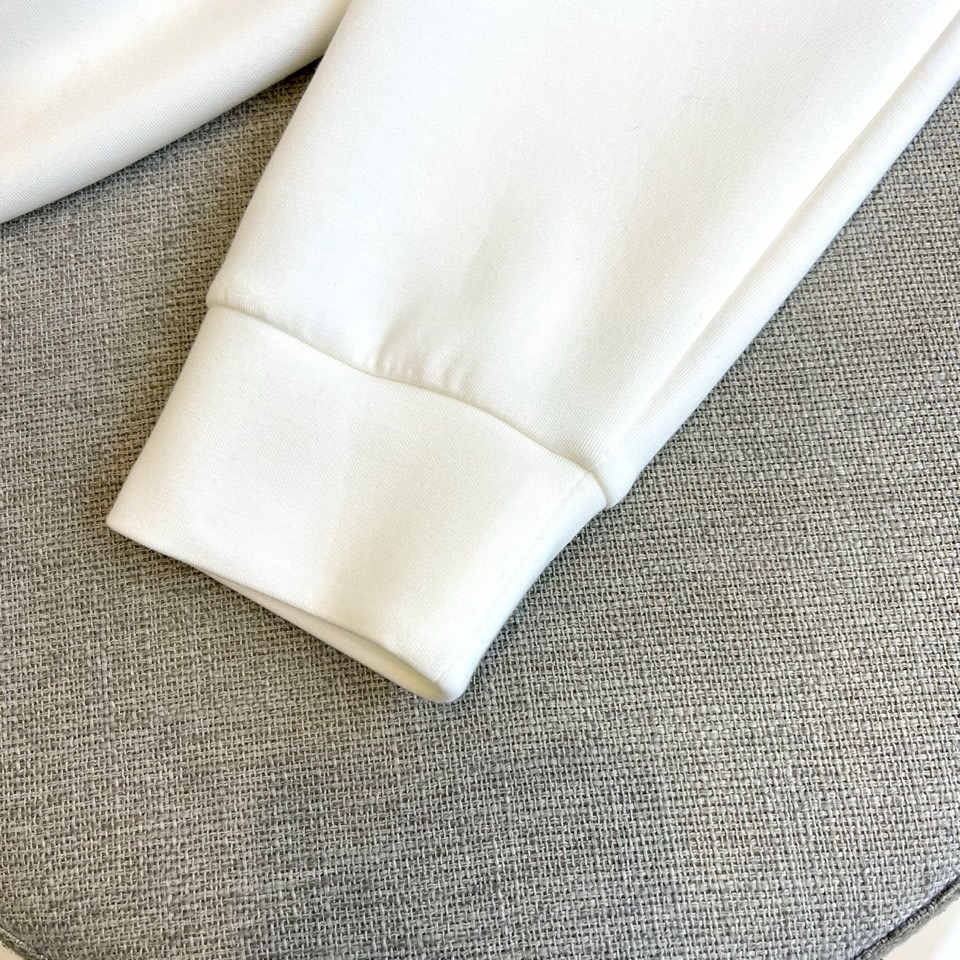 Prad普拉、2025秋冬长袖T恤卫衣。左胸椭圆形金色徽标镌刻品牌基因，领口内侧格纹暗藏经典传承——这是