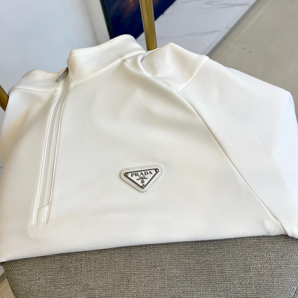 Prad普拉、2025秋冬长袖卫衣T恤。PRADA白色长袖打底衫，以半拉链立领设计诠释现代主义精髓。左胸
