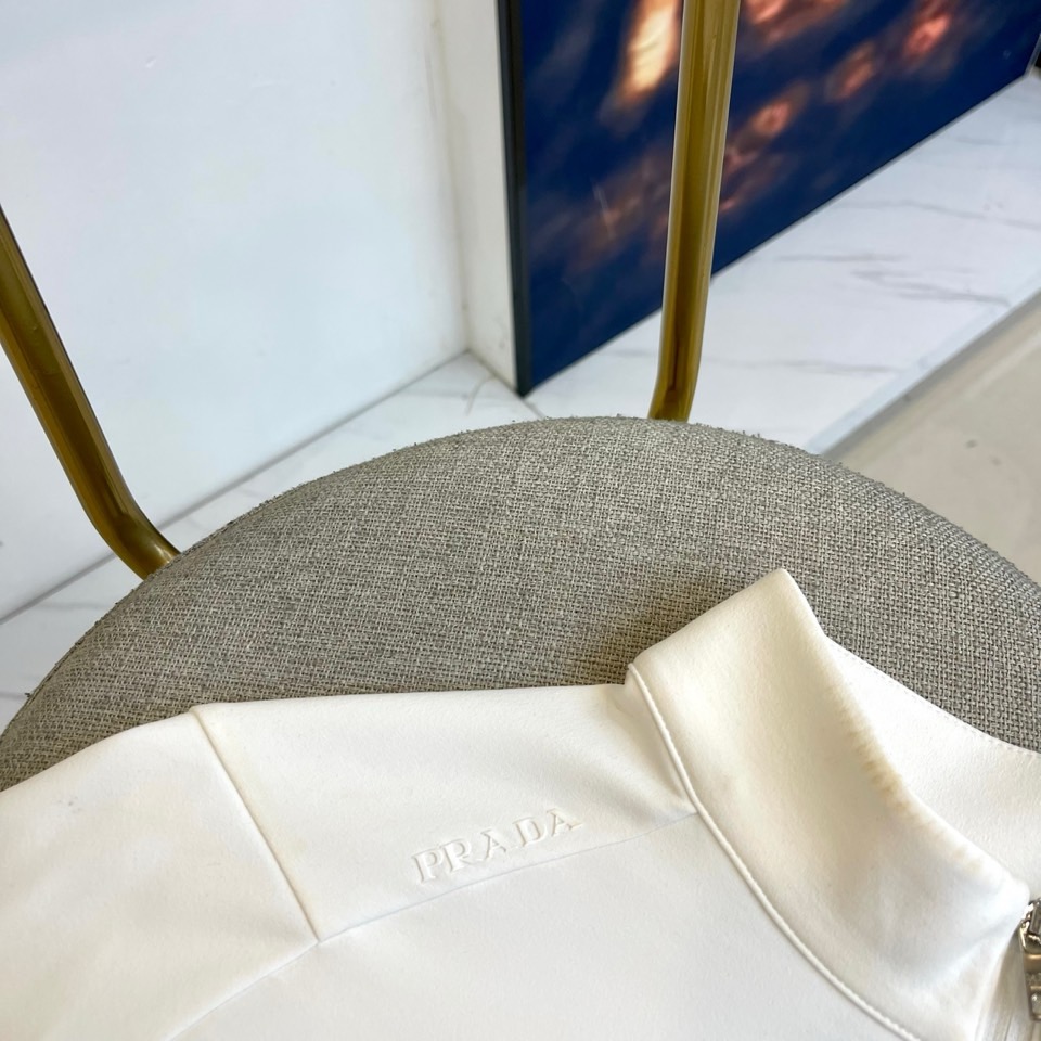 Prad普拉、2025秋冬长袖卫衣T恤。PRADA白色长袖打底衫，以半拉链立领设计诠释现代主义精髓。左胸