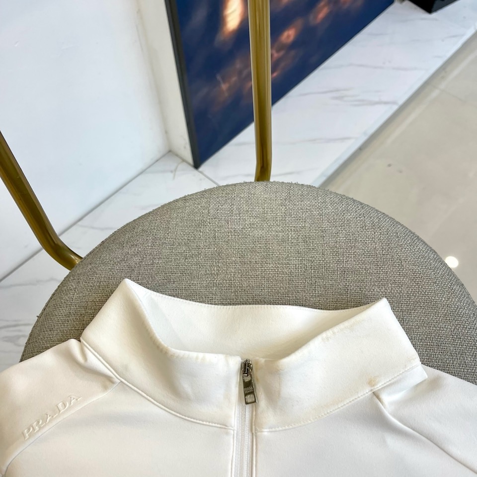 Prad普拉、2025秋冬长袖卫衣T恤。PRADA白色长袖打底衫，以半拉链立领设计诠释现代主义精髓。左胸