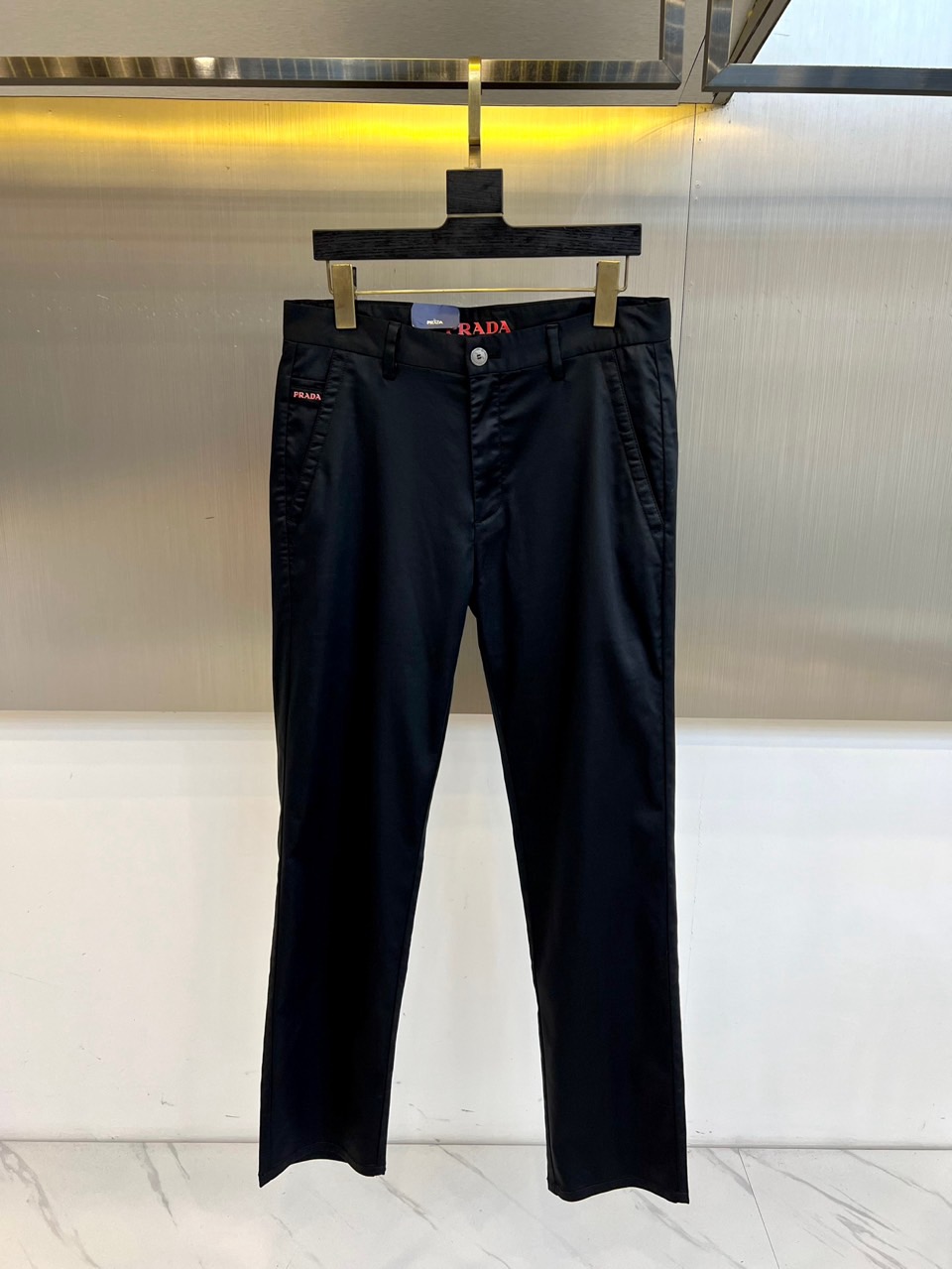 Prad普拉、2025秋冬新品商务休闲长裤。一抹红色，足以定义身份。这条PRADA黑色休闲长裤以极简轮廓