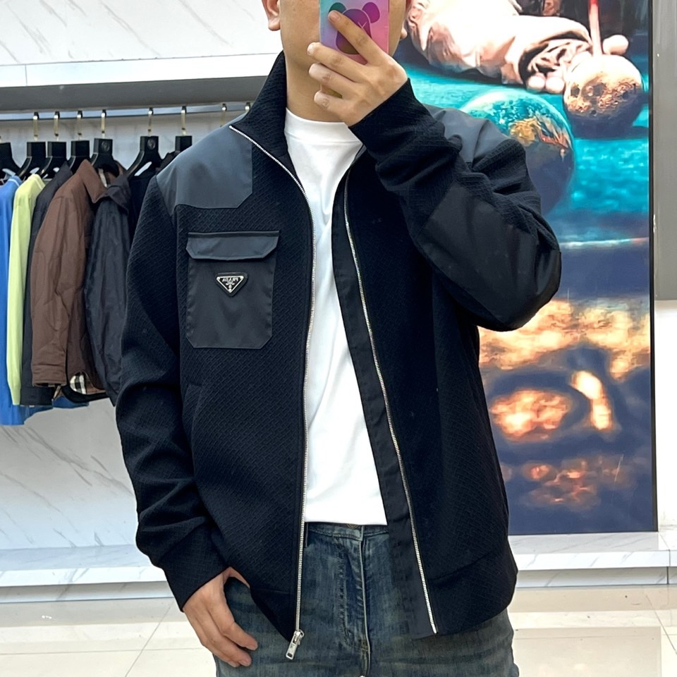 Prad普拉、25FW秋冬新品 黑色针织夹克外套。• 经典徽章加持：左胸翻盖口袋饰以PRADA标志性三角