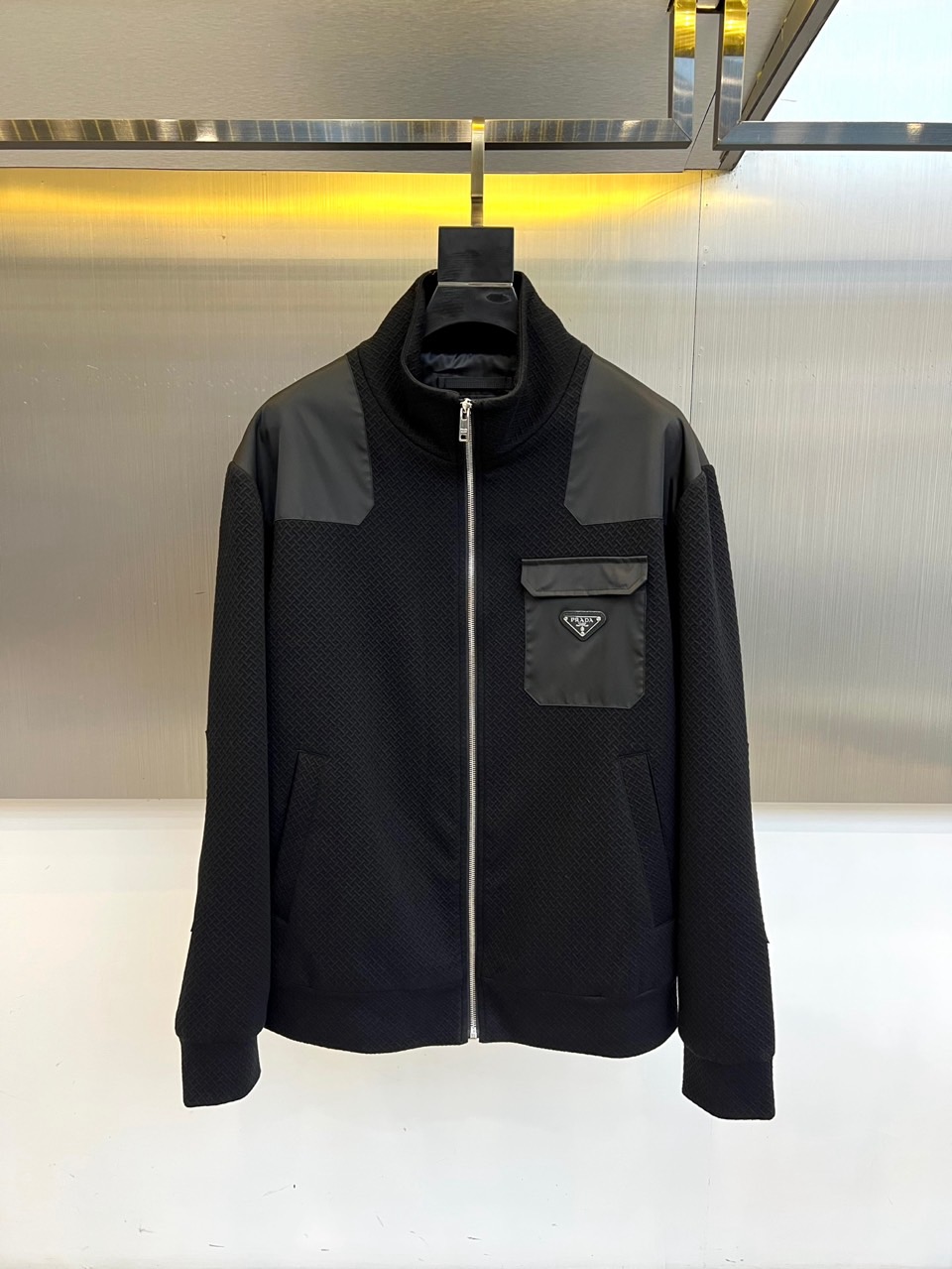 Prad普拉、25FW秋冬新品 黑色针织夹克外套。• 经典徽章加持：左胸翻盖口袋饰以PRADA标志性三角