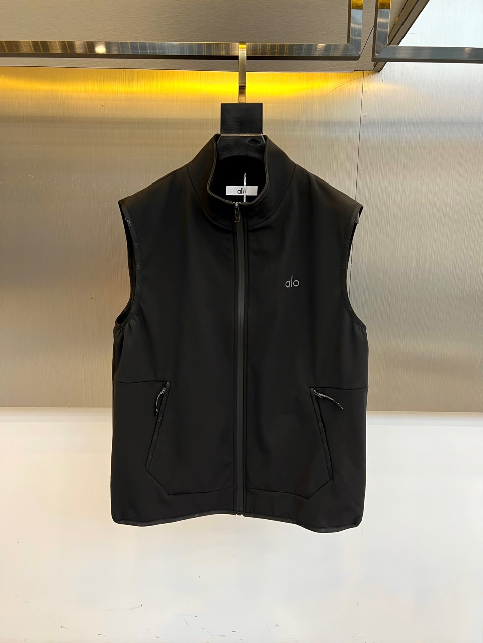 NO:527513,ALO new sleeveless vest in autumn and winter. Three-dimensional tailored sleeveless design frees the space of the two arms moving, with a standing collar structure and a through-type zipper to create neat shoulder and neck lines. The iconic identity logo embroidered with light-colored 'alo' logo on the left chest, announcing the brand genes with subtle details. The multi-functional pocket system has a double-sided hidden zipper pocket, which takes into account storage functions and smooth contours, and the items are traceless. Urban cycling, gym shuttle, night parties, and technological space check-in... A 'light functional equipment' that spans sports and streets. It can be layered alone, instantly improving the overall sense of layering and sporty fashion. 48-56 (model 173, 143 catties upper body 50 yards),,alexander wang19860909ALO 秋冬新品无袖机能马甲. 立体剪裁无袖设计解放双臂活动空间,立领结构搭配贯穿式拉链,塑造利落肩颈线条. 标志性身份标识左胸绣印浅色「alo」徽标,以微妙细节宣告品牌基因. 多功能口袋系统双侧隐藏式拉链口袋,兼顾储物功能与流畅轮廓,随身物品随行无痕. 城市骑行、健身房穿梭、夜间聚会、科技感空间打卡…一件跨越运动与街头的「轻机能装备」.单穿叠搭皆可,瞬间提升整体层次感与运动时尚度.48-56（模特173,143斤上身50码）,,alexander wang,Men's clothing