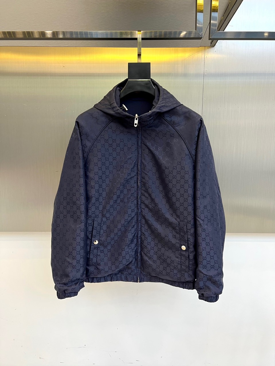 NO:539040,Gucc and Gucc and the new Gucc double-sided jackets in 2025 autumn and winter, interpreting the brand's classic aesthetics with innovative double-sided design. On one side, navy blue fabric is used to create a modern urban style, the hooded design is matched with silver zipper closure, the left chest is decorated with an iconic double G metal logo, the sleeves are decorated with red and blue webbing striped details, and practical pockets with zippers are equipped on both sides. On the other side, the dark blue GG presbyopia pattern is presented, and the classic brand logo is printed, forming a design echo through the silver snap-bar pocket and zipper closure. Both sides are made of high-tech functional fabrics, with windproof and warmth characteristics, and the cuffs and hem adopt elastic edge-closing technology. The flip-fitting can be worn to achieve two styles of navy blue to show the style of sports and fashion, and the GG presbyterian face interprets the retro and luxurious temperament. The three-dimensional tailoring maintains the neat silhouette of the brand, suitable for urban social, casual travel, daily commuting and other occasions. The Italian fine craftsmanship combines classic symbols with modern functions, and realizes the practical philosophy of wearing multiple clothes through double-sided design, becoming a signature item in the autumn and winter wardrobe of fashionable people that is both recognizable and functional. 48-56 (model 173, 143 catties upper body 50 yards),,gucci,gucci,jackets & coats,hats,alexander wang19860909Gucc古驰、2025秋冬新品Gucc双面穿夹克,以创新双面设计诠释品牌经典美学.一面采用藏青色面料打造现代都市风格,连帽设计搭配银色拉链开合,左胸饰有标志性双G金属logo,袖侧点缀红蓝织带条纹细节,两侧配备带拉链的实用口袋.另一面呈现深蓝色GG老花图案,满印经典品牌标识,通过银色按扣口袋与拉链开合形成设计呼应. 双面均采用高科技功能性面料,具备防风保暖特性,袖口与下摆采用弹性收边工艺.可翻转穿着实现两种风格藏青面展现运动时尚风范,GG老花面诠释复古奢华气质.立體剪裁保持品牌利落廓形,适合都市社交、休闲出行、日常通勤等多种场合.以意大利精工技艺将经典符号与现代机能融合,通过双面穿设计实现一衣多穿的实用哲学,成为时尚人士秋冬衣橱中兼具辨识度与功能性的标志性单品.48-56（模特173,143斤上身50码）,,gucci,gucci,jackets & coats,hats,alexander wang,Men's clothing