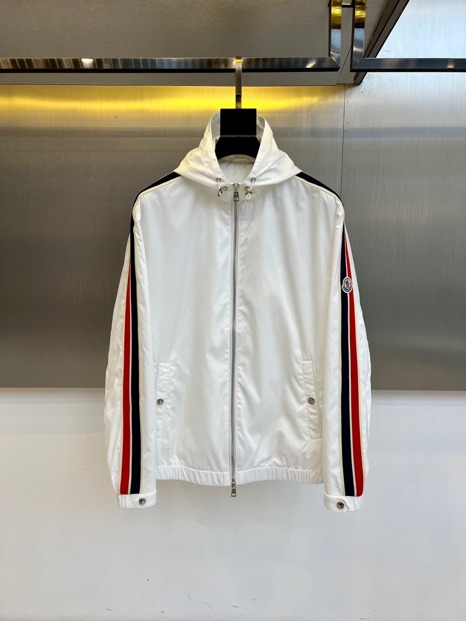 NO:529005,Monmon, 2025 autumn and winter new white hooded jacket, made of pure white high-tech functional fabric, combining light texture and excellent warmth performance. The style design is simple and neat and hooded with metal fasteners details, adding practical function; the front closure is smooth with zipper opening and closing; both sides of the sleeves are decorated with eye-catching red and black contrasting stripes, breaking through the pure white tone and injecting sports vitality; the brand logo is embellished above the left sleeve, showing off the identity in a low-key manner. The tailoring takes into account slimness and freedom of movement, and the hem and cuffs are fitted to enhance windproof and warmth. In terms of style, this jacket is perfect  Combining high-end sports style with modern urban aesthetics, the white main tone gives a minimalist and high-end feeling, and the red and black striped details break the monotony and add a dynamic atmosphere. It not only continues the traditional technological pragmatism gene of the hood, but also shows exquisite charm through color contrast and detailed craftsmanship. It is suitable for wearing on various occasions - whether it is daily leisure, outdoor activities or urban commuting, it can be easily matched with sweaters, casual trousers or sports items, showing a calm and stylish winter style. 48-56 (model 173, 143 catties upper body 50 sizes), Moncler, jackets  & coats,hats,alexander wang19860909Mon蒙、2025秋冬新品白色连帽夹克,以纯净白色高科技功能性面料打造,兼具轻盈质感与出色保暖性能.款式设计简约利落连帽配备金属扣件细节,增添实用机能感；前襟采用顺滑拉链开合,闭合流畅；袖身两侧饰以醒目的红黑对比色条纹,突破纯白基调,注入运动活力；左袖上方点缀品牌标志,低调彰显身份.剪裁兼顾修身与活动自由度,下摆与袖口采用贴合设计,提升防风保暖性.风格上,这款夹克完美融合高端运动风与现代都市美学,白色主调赋予极简高级感,红黑条纹细节则打破单调,增添动感气息.它既延续了蒙口一贯的科技实用主义基因,又通过色彩对比与细节工艺展现精致魅力,适合多种场合穿搭——无论是日常休闲、户外活动或都市通勤,都能轻松搭配针织衫、休闲长裤或运动单品,展现从容不失格调的冬日型格.48-56（模特173,143斤上身50码）,,Moncler,jackets & coats,hats,alexander wang,Men's clothing