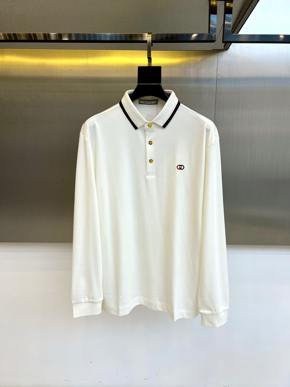 NO:529020,Gucc and the new long-sleeved Polo shirts in 2025 autumn and winter, interpret the elegant Italian aesthetics with classic Polo collar design. The neckline and placket are decorated with black thin edge strips, which contrasts sharply with the iconic double G logo embroidery on the left chest, showing the brand identity in a low-key manner. The slim and neat tailoring and long-sleeved design perfectly match the wear needs of autumn and winter. It is made of high-quality cotton blend fabric, which is soft and skin-friendly while maintaining a crisp texture. The pure white base tone is matched with eternal black gold details, continuing Gucci's classic color matching philosophy. The fabric is breathable and warm, ensuring comfort. The precise edge-closing process of the cuffs and hem reflects the exquisite Italian production level.  The overall style combines casual and exquisite luxury, which can not only match formal pants to show the charm of business casualness, but also pair it with jeans to highlight the fashion attitude. From the iconic double G embroidery to the detailed edging, each reflects Gucci's modern interpretation of classic elements, becoming a must-have item in the autumn and winter wardrobe that has both practical wearability and brand recognition. It is recommended to professional dry cleaning and maintenance to maintain the texture and style of the fabric. M-4XL (model 173, 143 catties upper body L size), gucci, gucci, jeans, alexander wang19860909Gucc古驰、2025秋冬新品长袖Polo衫,以经典Polo领设计诠释意式优雅美学.领口与门襟处饰有黑色细边镶条,与左胸位置的标志性双G标识刺绣形成鲜明对比,低调彰显品牌身份.修身利落的剪裁搭配长袖设计,完美适配秋冬季节的穿着需求. 采用高品质棉质混纺面料打造,柔软亲肤的同时保持挺括质感.纯净白色基调搭配永恒黑金细节,延续古驰经典配色哲学.面料兼具透气性与保暖性,确保穿着舒适度.袖口与下摆的精准收边工艺体现精湛意式制作水准. 整体风格融合休闲感与精致奢华感,既能搭配正装裤展现商务休闲魅力,亦可搭配牛仔裤凸显时尚态度.从标志性双G刺绣到细节镶边处理,每一处都体现古驰对经典元素的现代诠释,成为秋冬衣橱中兼具实穿性与品牌辨识度的必备单品.建议专业干洗保养以保持面料质感与版型挺括.M-4XL（模特173,143斤上身L码）,,gucci,gucci,jeans,alexander wang,Men's clothing