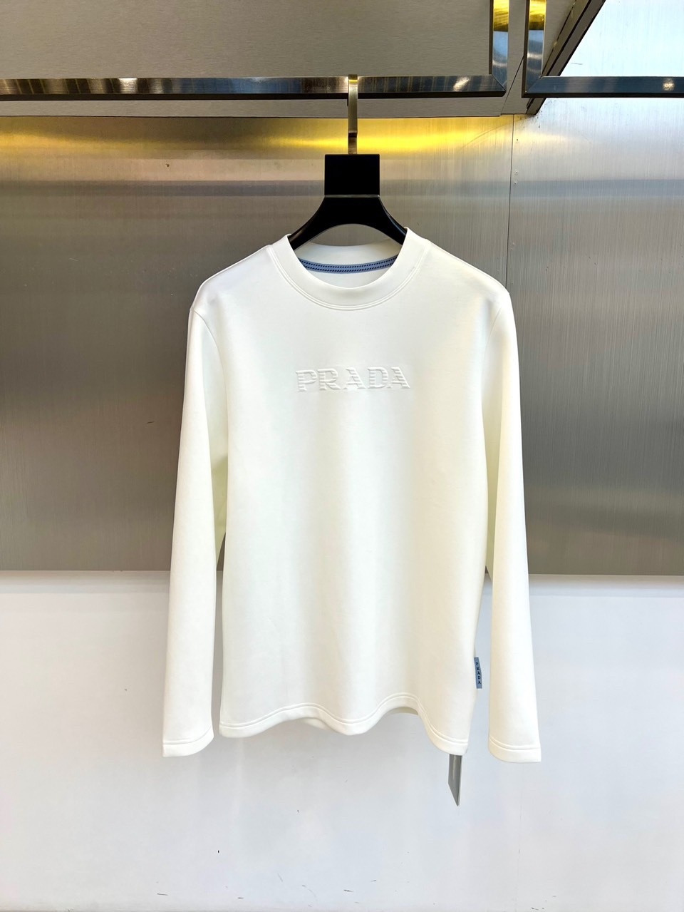 NO:529039,Prad Prada, 2025 autumn and winter new men's white long-sleeved T-shirt base shirt, interpreting modern luxury with minimalist aesthetics. This product uses 320 grams of water cubic air-layer fabric, containing scientific ratios of 42.5 recycled cellulose fiber, 41 cotton, 10.5 polyester fiber and 6 spandex to achieve a perfect balance between lightness, fluffy and three-dimensional integrity. The classic round neck design is lined with blue and white stripes, and the front is decorated with three-dimensional imprinted PRADA brand logo, which is low-key to highlight the brand genes. Loose tailoring ensures that the body is naturally drooped,  The simple silhouette without extra decoration combines high-end texture and wear comfort. The pure white tone presents multi-scene adaptability, which can be worn alone to show a refreshing and neat urban style, and can also be perfectly layered as an inner layer, suit and jacket. Prada uses exquisite craftsmanship and contemporary design language to reshape daily basic styles into a must-have item that combines a sense of technology and luxury, meeting the all-round needs of modern gentlemen for quality life. M-4XL (model 173, 143 catties upper body L size), prada, prada, jackets  & coats,tees,t-shirt,business suit,alexander wang19860909Prad普拉达、2025秋冬新品男士白色长袖T恤打底衫,以极简主义美学诠释现代奢华.本品采用320克水立方空气层面料,含42.5再生纤维素纤维、41棉、10.5聚酯纤维与6氨纶的科学配比,实现轻盈蓬松与立体挺括的完美平衡.经典圆领设计内衬蓝白相间条纹细节,正面饰有立体压印PRADA品牌标识,低调彰显品牌基因.宽松剪裁确保衣身自然垂坠,无多余装饰的简约廓形兼具高级质感与穿着舒适度.纯白色调呈现多场景适配性,既可单穿展现清爽利落的都市风格,亦能作为内搭与西装、外套完美叠穿.普拉达以精湛工艺与当代设计语言,将日常基础款重塑为兼具科技感与奢华感的必备单品,满足现代绅士对品质生活的全方位需求.M-4XL（模特173,143斤上身L码）,,prada,prada,jackets & coats,tees，t-shirt,business suit,alexander wang,Men's clothing