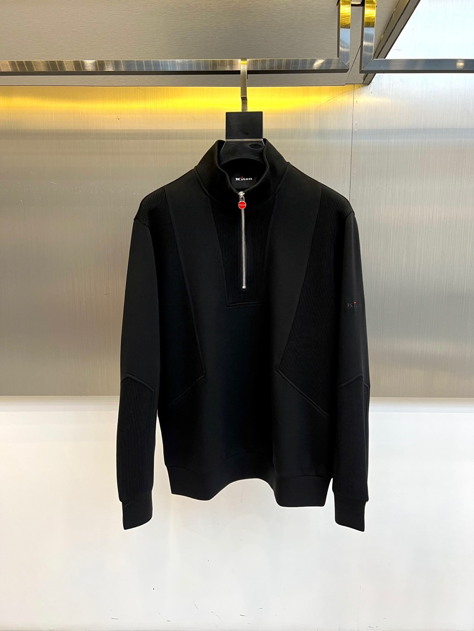 NO:595872,Kiton-2025 new autumn and winter half-high collar top interprets Italian elegant aesthetics with innovative splicing design. The half-high collar design is equipped with metal zipper opening and closing, and the zipper pull is embellished with eye-catching red details, becoming the visual focus of the overall design. The sleeves and chest use three-dimensional line splicing technology to build a three-dimensional silhouette through precise cutting. The left sleeve is decorated with the brand's classic logo badge.  The fabric is made of high-tech blended material. Material A contains 58.6 polyester fiber, 18.8 cotton, 18.8 viscose fiber and 3.8 spandex. Material B contains 60 viscose fiber and 40 polyester fiber. This innovative ratio not only maintains the stiffness of the fabric, but also gives excellent elasticity and skin-friendly comfort. The implementation standard complies with the GB18401 safety category to ensure the safety of direct contact with the skin.  The loose fit combines sports elements with advanced garment craftsmanship, and the white main tone and red details highlight low-key luxury. It can be paired with formal pants to show a business casual style, or casual pants to create a modern urban look. From the collar zipper to the three-dimensional splicing lines, every detail reflects Kiton's persistent pursuit of Italian exquisite craftsmanship.  This top is an ideal choice for layering systems in autumn and winter. The high-tech fabric ensures wearing comfort and long-lasting styling. It is recommended to hand wash in cold water and lay flat to dry to maintain the purity of the white fabric and the three-dimensional sense of the spliced structure. 48-56 (model 173, 143 pounds, upper body size 50), alexander wang19860909Kiton-2025秋冬新品半高领上衣,以创新拼接设计诠释意式优雅美学.采用半高领设计搭配金属拉链开合,拉链头点缀醒目的红色细节,成为整体设计的视觉焦点.衣袖与胸前运用立体线条拼接工艺,通过精准裁片构建立体轮廓,左袖处饰有品牌经典标识徽章. 面料选用高科技混纺材质A料含58.6聚酯纤维、18.8棉、18.8粘纤与3.8氨纶,B料含60粘纤与40聚酯纤维.这种创新配比既保持面料的挺括感,又赋予优异的弹性与亲肤舒适度.执行标准符合GB18401安全类别,确保直接接触皮肤的安全性. 宽松版型融合运动元素与高级成衣工艺,白色主调搭配红色细节彰显低调奢华.既可搭配正装裤展现商务休闲风范,亦可搭配休闲裤打造现代都市造型.从领口拉链到立体拼接线条,每处细节都体现Kiton对意式精湛工艺的执着追求. 这件上衣成为秋冬季节叠穿体系的理想选择,高科技面料确保穿着舒适度与造型持久性.建议冷水手洗并平铺晾干,以保持白色面料的纯净度与拼接结构的立体感.48-56（模特173,143斤上身50码）,,alexander wang,Men's clothing