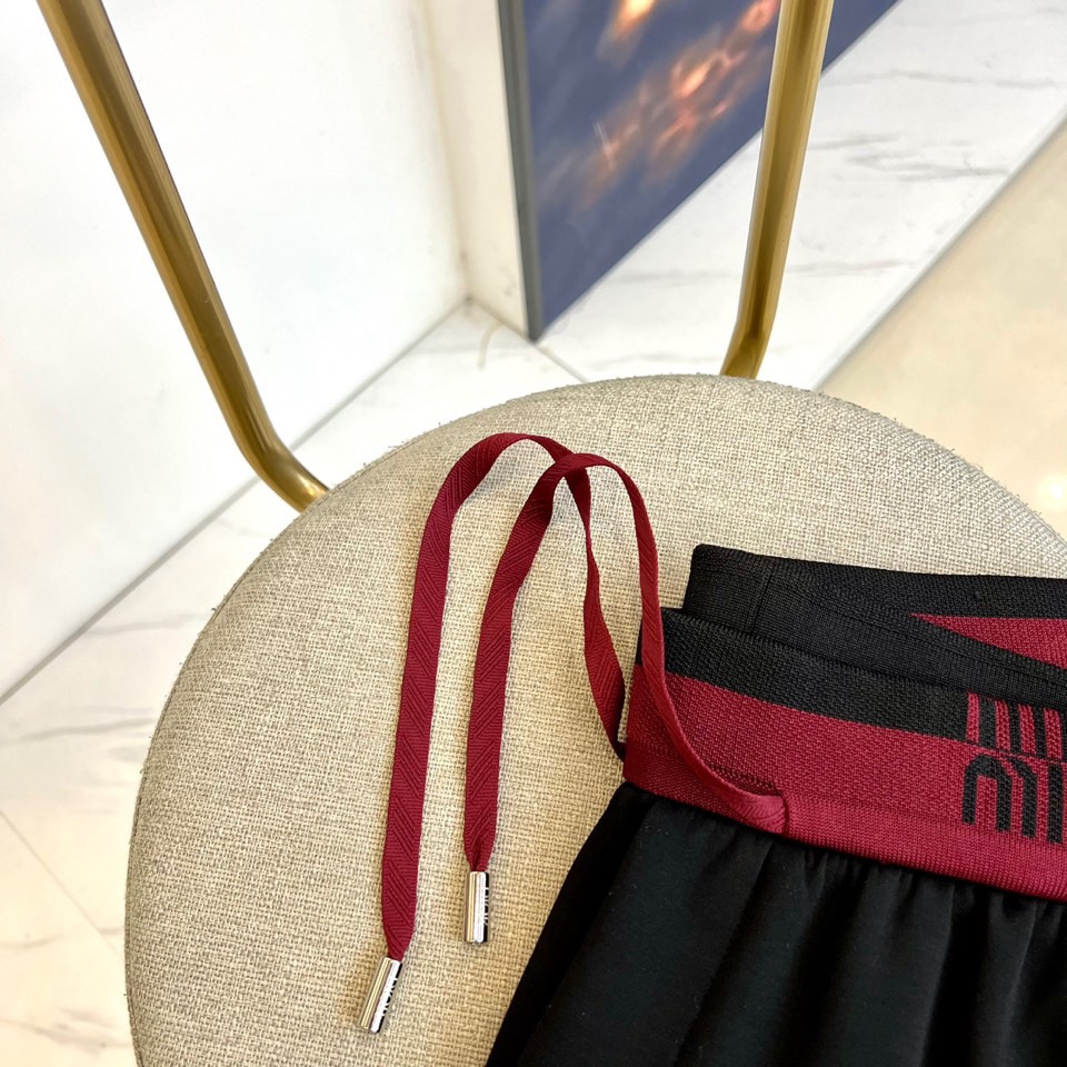 Miu Miu 2025秋冬新品米白色休闲裤，以纯净色调演绎现代少女式叛逆。腰头处饰有酒红色镶边撞色设计