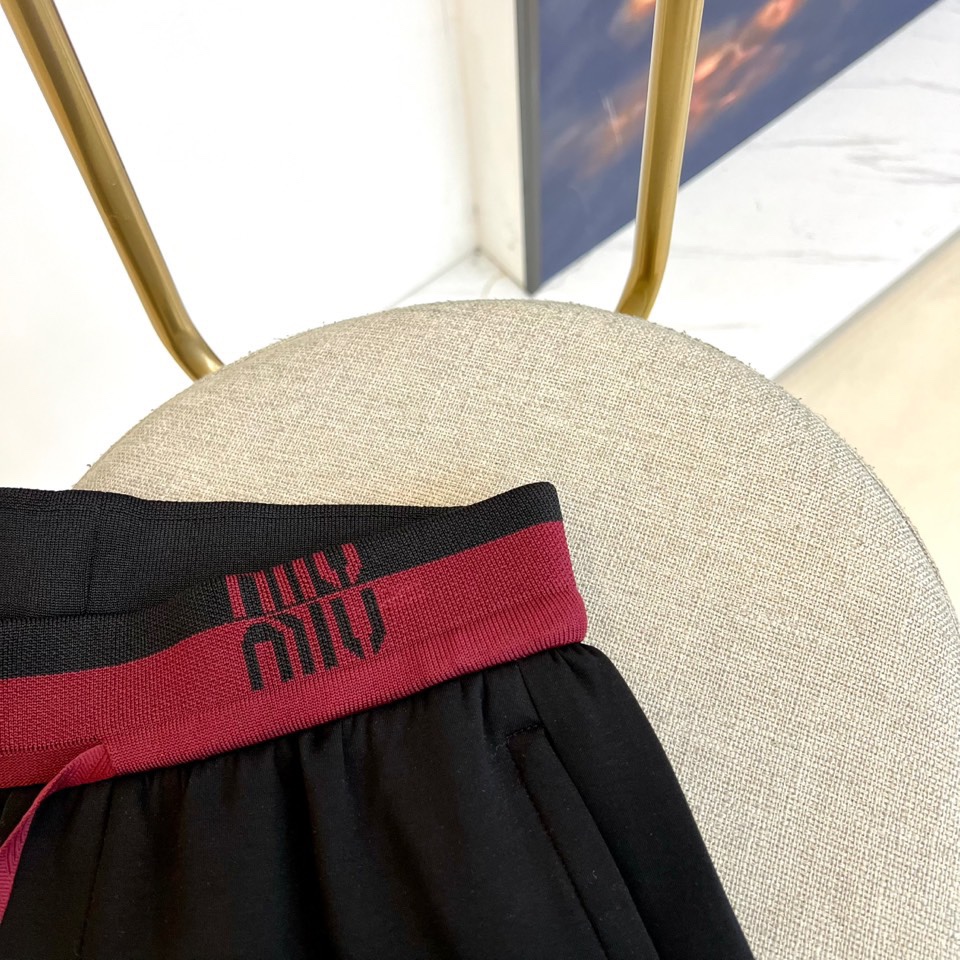 Miu Miu 2025秋冬新品米白色休闲裤，以纯净色调演绎现代少女式叛逆。腰头处饰有酒红色镶边撞色设计