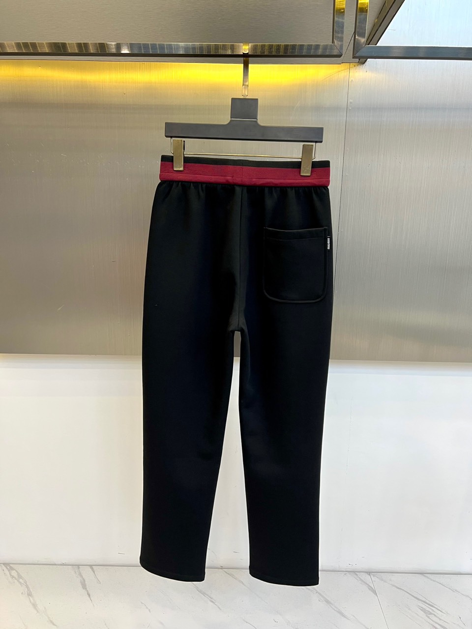 Miu Miu 2025秋冬新品米白色休闲裤，以纯净色调演绎现代少女式叛逆。腰头处饰有酒红色镶边撞色设计