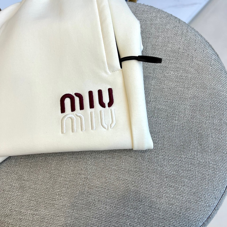 Miu Miu 2025秋冬新品米白色休闲裤，以纯净色调演绎现代少女式叛逆。腰头处饰有酒红色镶边撞色设计