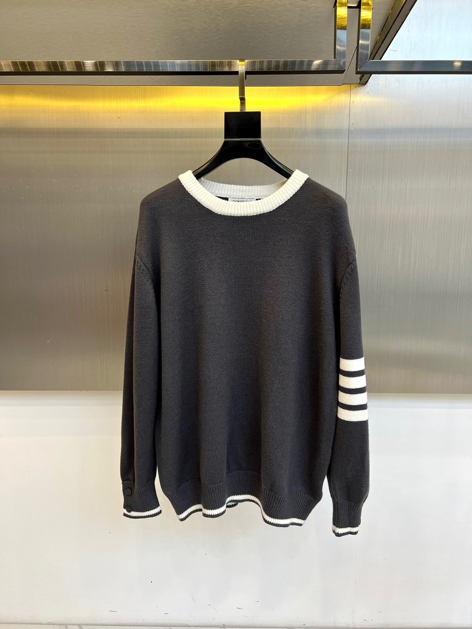 TB 2025秋冬新品深灰色针织毛衣，以经典圆领设计与标志性条纹元素诠释现代学院风美学。呈现细腻的深灰色