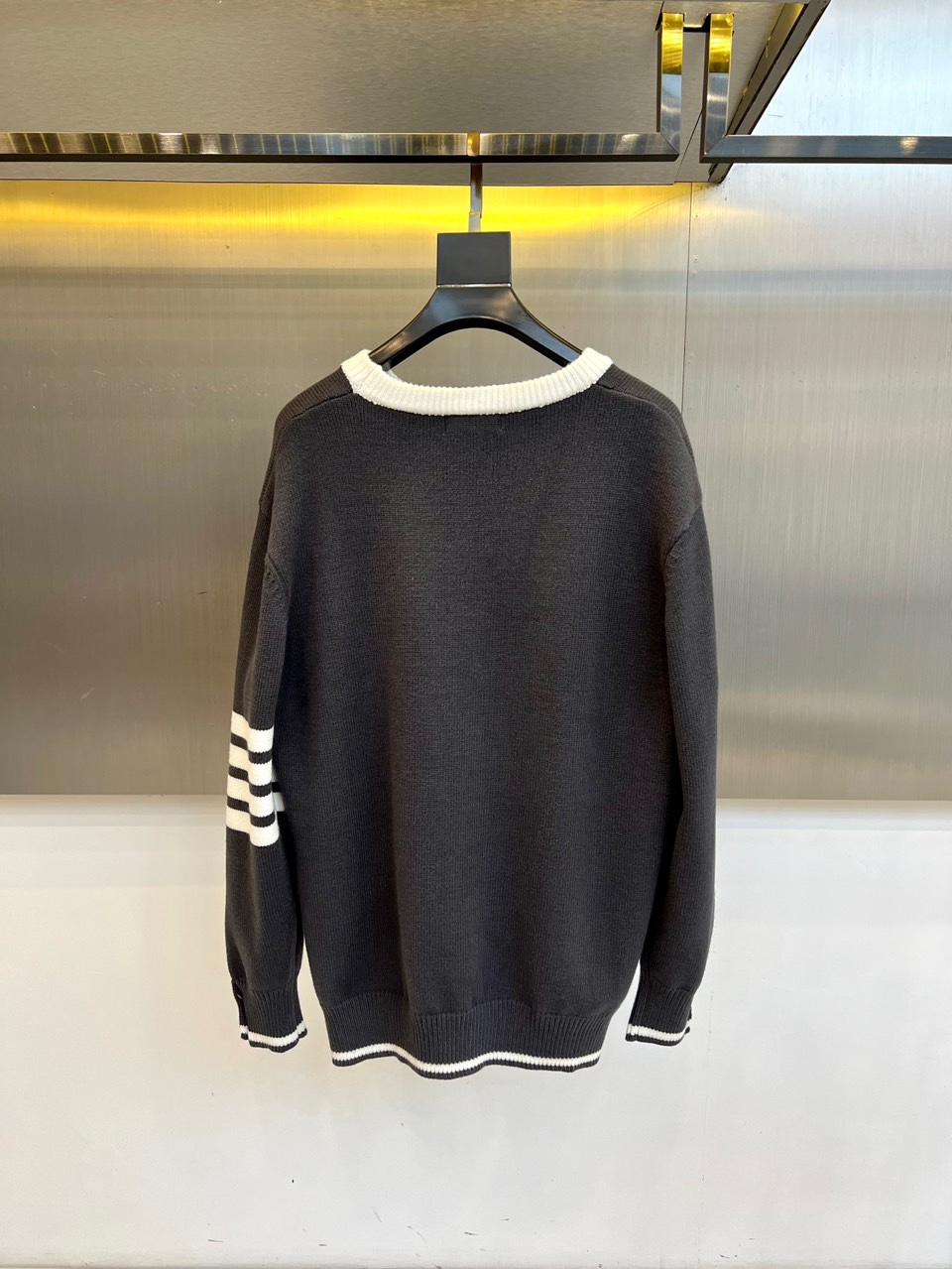 TB 2025秋冬新品深灰色针织毛衣，以经典圆领设计与标志性条纹元素诠释现代学院风美学。呈现细腻的深灰色