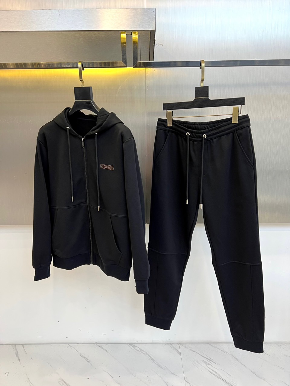 NO:595850,Zegna, the new luxury sports suit for autumn and winter 2025, redefines urban casual style with high-end gray tones. The top adopts a hooded zipper sweatshirt style, embellished with the classic ZEGNA logo on the left chest, low-key highlighting the brand genes. The three-dimensional pockets on the front combine practicality and design, and the bottoms are matched with the same color leggings. The waist drawstring and side slant pockets are designed to enhance overall functionality. The suit is made of high-quality fabrics to create a smooth touch and excellent drape, and the neat tailoring is a perfect balance  Casual sense and sophistication. The overall style combines Italian elegance and modern sports aesthetics, which can not only meet the comfort needs of daily travel, but also manage a variety of leisure occasions, interpreting the calm and extraordinary modern gentleman style. Whether it is a morning jog or a weekend get-together, it can show a calm charm that transcends the occasion. 48-56 (model 173,143 pounds, upper body size 50),,zegna,hoodie,sweatshirts,hats,alexander  wang19860909Zegna杰尼亚、2025秋冬新品奢华运动套装,以高级灰色调重新定义都市休闲风尚.上衣采用连帽拉链卫衣款式,左胸点缀经典ZEGNA标识,低调彰显品牌基因.前侧立体口袋兼顾实用与设计感,下装搭配同色束脚运动裤,腰部抽绳与侧边斜插口袋设计提升整体功能性.套装选用高品质面料打造柔滑触感与出色垂坠度,利落剪裁完美平衡休闲感与精致度.整体风格融合意式优雅与现代运动美学,既能满足日常出行的舒适需求,亦能驾驭多种休闲场合,诠释从容不凡的现代绅士风范.无论是晨间慢跑或是周末小聚,皆能展现超越场合的从容魅力.48-56（模特173,143斤上身50码）,,zegna,hoodie,sweatshirts,hats,alexander wang,Men's clothing