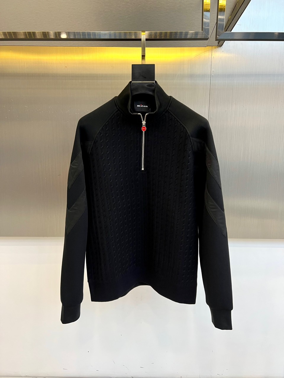 NO:595859,Kiton-2025 new autumn and winter knitted top interprets Italian elegant aesthetics with a half-high collar design and metal zipper structure. The zipper pull is embellished with iconic red details, becoming the visual focus of the overall design. The body adopts a precision woven texture, and the shoulders and sleeves cleverly use diamond-shaped plaid splicing technology to build a three-dimensional hierarchy through the collision of different weaving methods. The left sleeve is decorated with the brand's classic emblem, low-key highlighting the identity.  The fabric is made of a blend of 47 cotton and 53 polyester fiber, which not only maintains the skin-friendly comfort of cotton, but also has the stiffness and durability of polyester fiber. The loose fit combines sports elements with advanced garment craftsmanship, and the white main tone and red details highlight low-key luxury.  The overall style perfectly balances casualness and refined aesthetics. It can be paired with formal pants to show a business casual style, or casual pants to create a modern urban look. From the diamond splicing process to the red zipper details, every design reflects Kiton’s exquisite Italian craftsmanship.  The persistent pursuit of low-temperature hand washing and maintenance tips ensures that the item will last as long as new, making this top a must-have item that is both practical and brand-recognizable in autumn and winter. 48-56 (model 173, 143 pounds, upper body size 50),,alexander  wang19860909Kiton-2025秋冬新品针织上衣,以半高领设计与金属拉链结构诠释意式优雅美学.拉链头点缀标志性红色细节,成为整体设计的视觉焦点.衣身采用精密编织纹理,肩部与袖管巧妙运用菱形格纹拼接工艺,通过不同织法的碰撞构建立体层次.左袖处饰有品牌经典徽章,低调彰显身份. 面料选用47棉与53聚酯纤维混纺材质,既保持棉质的亲肤舒适感,又兼具聚酯纤维的挺括度与耐久性.宽松版型融合运动元素与高级成衣工艺,白色主调搭配红色细节彰显低调奢华. 整体风格完美平衡休闲感与精致美学,既可搭配正装裤展现商务休闲风范,亦可搭配休闲裤打造现代都市造型.从菱形拼接工艺到红色拉链细节,每处设计都体现Kiton对意式精湛工艺的执着追求.低温手洗保养提示确保单品持久如新,使这件上衣成为秋冬季节兼具实穿性与品牌辨识度的必备单品.48-56（模特173,143斤上身50码）,,alexander wang,Men's clothing