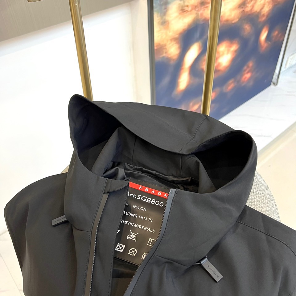 Prada普拉、2025秋冬新品连帽外套，以极致简约的线条诠释现代实用主义美学。采用高科技哑光黑色面料打