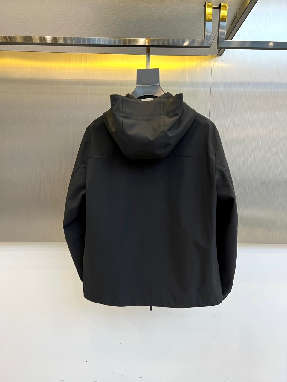 Prada普拉、2025秋冬新品连帽外套，以极致简约的线条诠释现代实用主义美学。采用高科技哑光黑色面料打