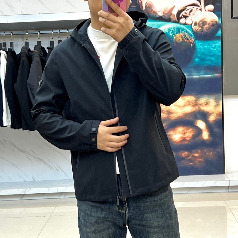 Prada普拉、2025秋冬新品连帽外套，以极致简约的线条诠释现代实用主义美学。采用高科技哑光黑色面料打