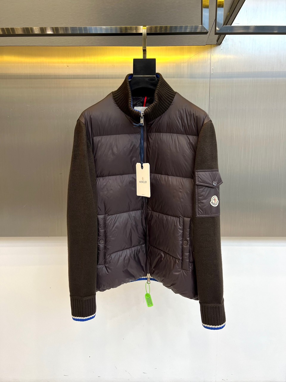 NO:539032,Mon cover (goosevelt), 25FW autumn and winter new knitted styling down jacket. The dark brown nylon torso is like a seiko-forged armor, but the blue and white striped knitted sleeves hidden soft genes. The metal badge on the three-dimensional pocket of the left arm forms a color collision with the blue edge of the neckline. When hung on the metal wall, the white label hanging on the zipper head becomes the visual anchor point of the entire shape. 90 Pure Goosevelt Extreme Cold Declaration American Standard Certification, each gram of velvet is a polar adventure-level luxury. The blue and white cuff stripes hide non-Newtonian fluid elastic technology. The six-language wash mark reflects global quality under warm light 1. The entire zipper series + knitted collar stands up = blizzard defense form 2. The cuff blue and white stripes turn outward = urban functional mode 1-5 (model 173, 143 catties upper body 2 sizes), Moncler, down  Jacket,alexander wang19860909Mon蒙口（鹅绒）、25FW秋冬新品针织拼接羽绒服 深棕尼龙躯干如精工锻造的铠甲,蓝白条纹针织袖管却暗藏柔软基因.左臂立体口袋上的金属徽章与领口蓝边形成色彩对撞,悬挂于金属墙面时,拉链头悬挂的白标吊牌成为整个造型的视觉锚点. 90纯鹅绒的极寒宣言 美国标准认证,每克绒朵都是极地探险级的奢侈 蓝白袖口条纹暗藏非牛顿流体般的弹性科技 六国语言洗标在暖光下折射出全球化品质 1. 拉链全系+针织领立起=暴风雪防御形态 2. 袖口蓝白条纹外翻=都市机能模式 1-5码（模特173,143斤上身2码）,,Moncler,down jacket,alexander wang,Men's clothing